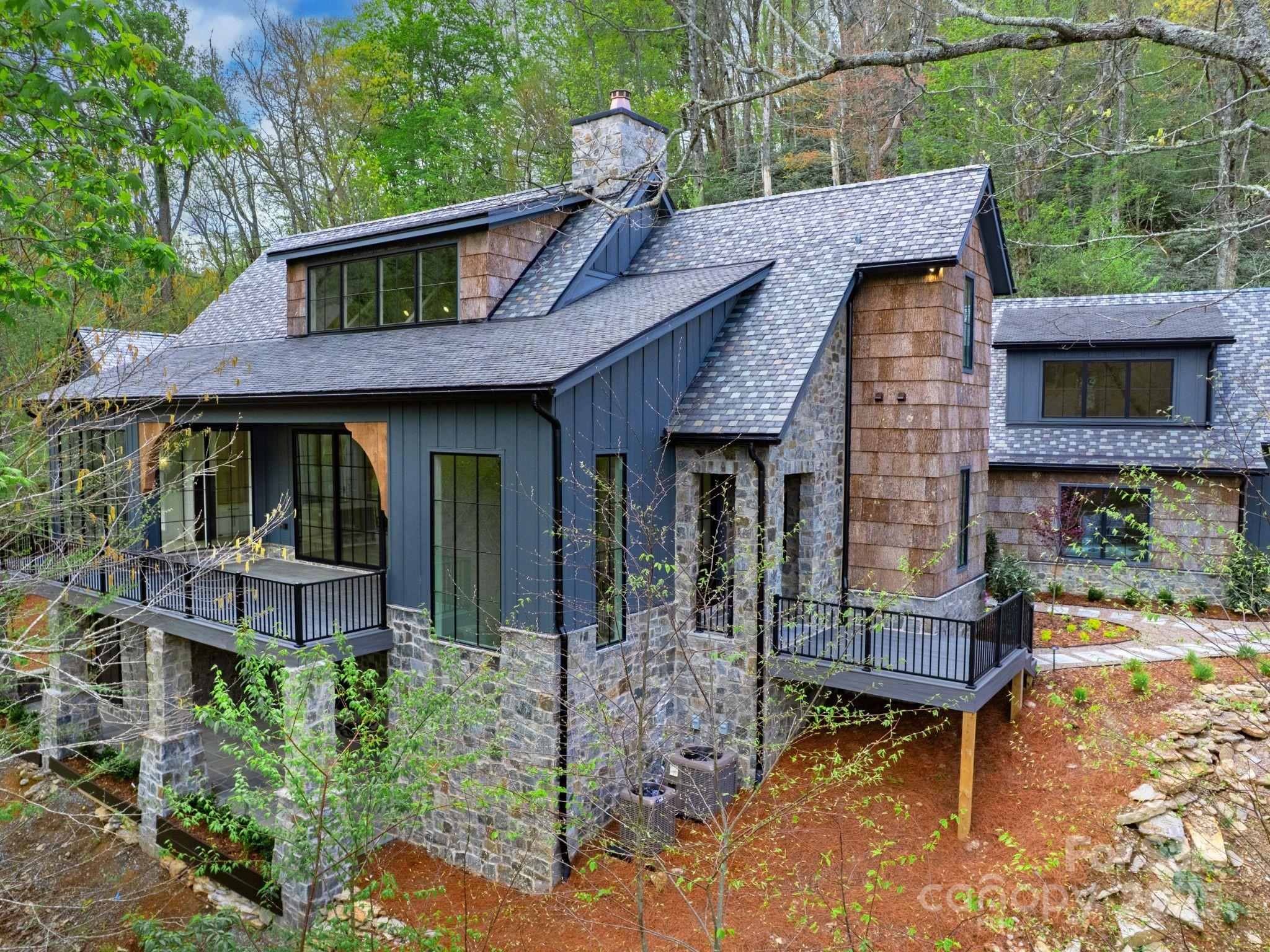 Beaver Lodge, built by DuBose Custom Homes, is a one of a kind mountain retreat designed by architect David O’Bryan. The retreat is meticulously sited overlooking New River Creek, stocked year round for trout fishing.
Located in the beautiful, gated resort community of Firethorn, only minutes from downtown Blowing Rock, Boone and the App Ski Basin. Beaver Lodge features a reclaimed slate roof, natural stone, white oak hardwoods, La Cornue gas range, custom cabinetry and designer lighting. The impressive two story stone fireplace is the centerpiece of an open concept living area with 20’ ceilings, exposed oak beams and spacious
outdoor living spaces on both the front and rear of the home. Four ensuite bedrooms. Primary with fireplace.  Two main living areas with fireplaces and a bonus flexible space that can be adapted for a home theater or bunk room. A two-car garage with a flexible space above includes a full bathroom and bar and is ideal for entertaining or office space.