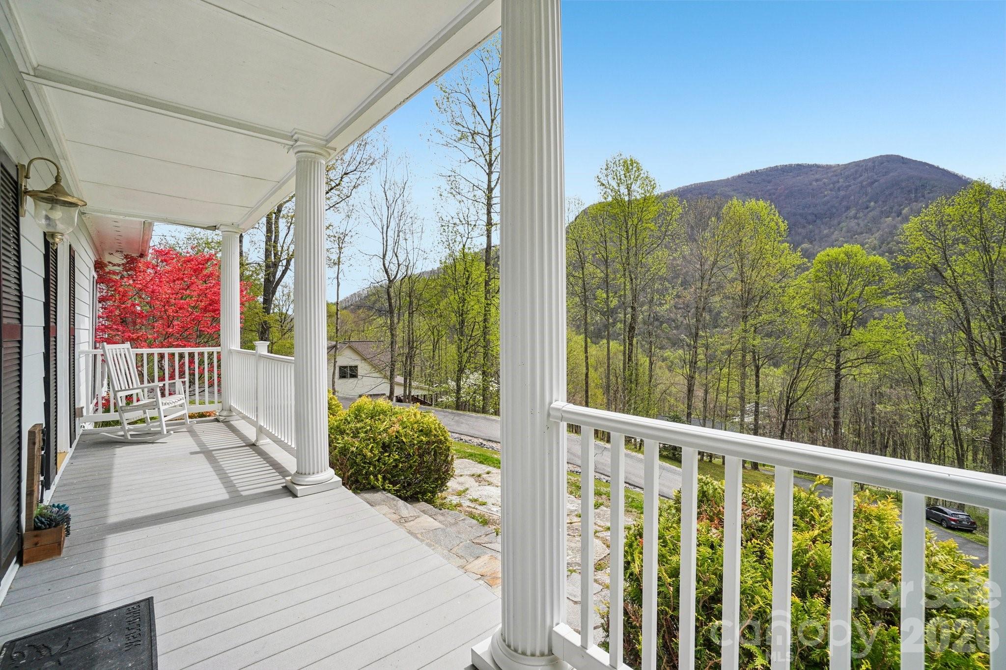 Short-term rentals allowed! Welcome to your dream mountain retreat in the heart of Maggie Valley! This stunning 4-bedroom, 2 full bath, 2 half bath home offers the perfect blend of classic elegance and mountain charm, nestled against a lush wooded backdrop with breathtaking views of the surrounding peaks. Step inside to a grand two-story foyer with rich hardwood floors, wainscoting, and a graceful staircase that sets the tone for the quality and craftsmanship found throughout. The expansive great room features a coffered ceiling, cozy fireplace flanked by custom built-ins, and French doors that open to the back deck — ideal for indoor-outdoor mountain living. The chef's kitchen impresses with white raised-panel cabinetry, granite countertops, stainless steel appliances, a center island with seating, and a tile backsplash, all flowing seamlessly into the casual dining area.  The primary suite offers a serene escape complete with a private office or sitting area and an en-suite bath with dual vanities. Three additional bedrooms provide ample space for family and guests, with a bonus flex room perfect for a second office, studio, or recreation space. Outside, enjoy the ultimate backyard oasis — a covered hot tub, spacious deck, stone fire pit, fully fenced yard, and sweeping mountain views that will take your breath away. A two-car garage and generous driveway complete this exceptional package.  All of this just minutes from Maggie Valley's shops, restaurants, skiing, and year-round outdoor recreation. This is Western North Carolina living at its finest — priced at $750,000.