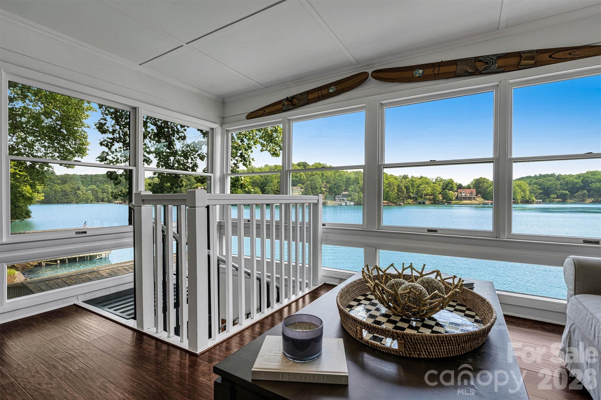 Fully Furnished, turnkey, impeccably maintained waterfront retreat on Lake Lure, showcasing sweeping, unobstructed BIG lake views. This exquisite three-bedroom, two-bath residence offers an exceptional blend of comfort and elegance, perfectly positioned at the water’s edge with deep water access directly off the private dock. A covered boathouse provides generous storage for watercraft and lake accessories. The main level features a serene primary suite and a beautifully renovated open-concept kitchen flowing seamlessly into the great room, anchored by a charming wood-burning fireplace. Sunlight pours into the inviting sunroom, where mornings begin with coffee and panoramic lake vistas that create the sensation of living directly on the water. The lower level offers two additional guest bedrooms, a full bath, a versatile flex space, and a conveniently located laundry closet—ideal for hosting family and friends. Outdoor living is elevated with a screened porch perfect for al fresco dining, while the private dock invites relaxation as boats glide by on the lake. A rare opportunity to own a thoughtfully designed Lake Lure home where timeless luxury meets effortless lakefront living.