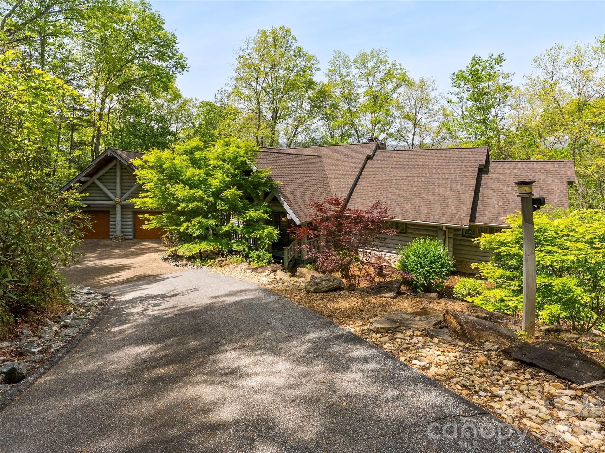 A truly exceptional offering, this premier luxury log home at 4004 Lake Adger Parkway in Mill Spring showcases breathtaking mountain and riverfront living at its finest. Set on a remarkably private homesite with over 600 feet along the Green River, the property captures sweeping views of three distinct mountain ridgelines, creating a layered backdrop that is nothing short of extraordinary.

Thoughtfully designed and meticulously maintained by its original owner, this home was built as a true labor of love with an uncompromising focus on quality and craftsmanship. The structure features 12 inch Canadian logs, complemented by 10 inch poured concrete foundation walls, providing both beauty and lasting integrity. Inside, character logs have been thoughtfully incorporated as architectural accents, adding warmth and visual interest throughout the home.

A long paved driveway leads you through a serene setting of mature trees and mountain laurel, opening to additional gravel parking that can easily accommodate an RV. The grounds are equally impressive, featuring extensive landscaping and hardscaping, a tranquil waterfall and koi pond, and private walking trails that wind throughout the property for both relaxation and recreation.

Inside, soaring 25 foot ceilings define the main living space and primary suite, complemented by rich hickory floors, solid wood doors, and expansive casement windows that frame the surrounding views. A dramatic floor to ceiling gas log fireplace anchors the living room, which flows seamlessly into a chef’s kitchen outfitted with granite countertops, tile backsplash, wrap around breakfast bar, and premium appliances including GE Monogram appliances, a Boschdishwasher, double wall ovens, five burner gas cooktop, wine refrigerator, trash compactor, and a walk in pantry with custom shelving.

The main level primary suite is a private retreat, complete with its own gas log fireplace, direct access to the rear deck, and a spa inspired bath featuring a corner jetted tub, triple vanities, a tiled shower with dual seating and shower heads, bidet, and a spacious walk in closet.

Additional main level features include a welcoming library with custom built in shelving, a powder room at the foyer, and a well appointed laundry and mud room with granite countertops, utility sink, and built in washer and dryer pedestals. A breezeway provides convenient access to the attached two car garage.

Upstairs, a loft style bedroom and full bath with custom tile shower offer a private guest retreat. The lower level expands the living space with travertine tile flooring, a large den with a wood burning freestanding fireplace, a river facing room filled with natural light, two additional bedrooms, a full bath, a heated and cooled storage room, and a dedicated mechanical space.

Outdoor living is equally well considered, with a wraparound porch featuring inlaid wood ceilings and granite porch caps, along with stainless steel cable railing designed to preserve the unobstructed mountain views. Additional features include a 500 gallon propane tank, a new roof installed in October 2024 with warranty, custom Tiffany style lighting from Raleigh, and integrated Polk Audio speakers both inside and out.

Located within the Lake Adger community, known for its natural beauty, equestrian friendly environment, and protected surroundings, this one of a kind property offers a rare opportunity to own a legacy home where craftsmanship, privacy, and setting come together seamlessly.