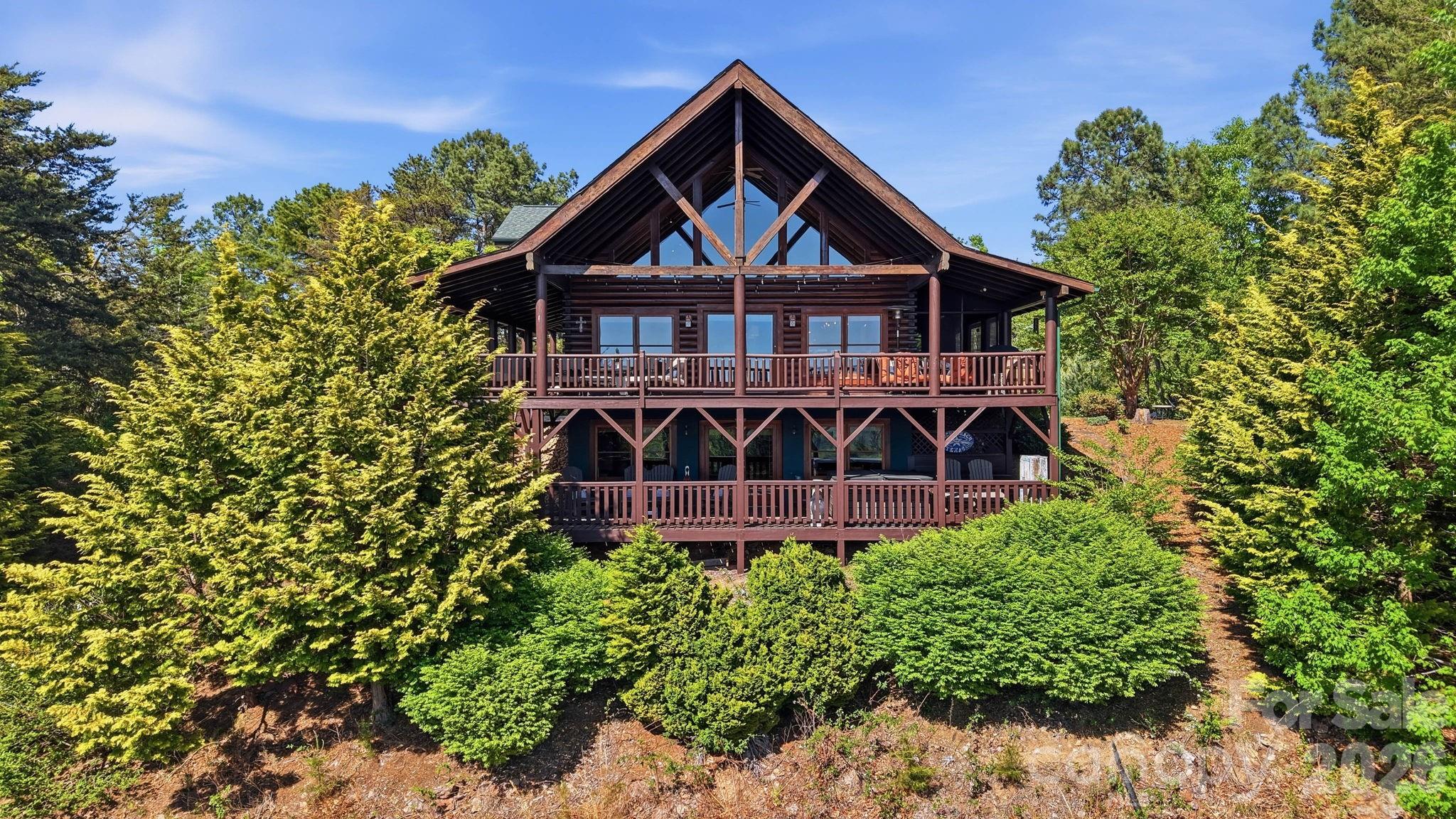 Perched high above the Blue Ridge landscape in the gated community of High Peak Mountain Estates, this extraordinary mountain retreat offers the kind of views most people only experience on scenic overlooks. From sunrise hues to unforgettable sunset skies, the long-range mountain vistas create a breathtaking backdrop for everyday living.

Designed to capture both comfort and connection to the outdoors, the home features soaring cathedral ceilings and expansive windows that fill the open-concept living spaces with natural light while framing the mountains beyond. A dramatic rock fireplace anchors the main living area, creating the perfect gathering space after a day exploring the mountains.

With approximately 4,100 square feet, this thoughtfully designed home offers 3 bedrooms and 4 baths, including convenient main-level living with a bedroom and laundry on the main floor. Upstairs, the spacious primary suite serves as a private retreat complete with a freestanding electric fireplace, spa-inspired bath with jacuzzi tub, dual vanity, and walk-in shower. A loft overlooking the living area provides flexible space for an office, reading nook, or additional lounge area.

The home was built with entertaining in mind. The finished lower level features a large recreation room with fireplace, a bar area with kitchenette, and an additional bedroom and full bath with sauna. With the pool table included, it's an ideal setting for hosting friends and family.

Outdoor living is equally impressive. Three covered decks, including a screened porch and a private balcony off the primary suite, offer multiple spaces to take in the surrounding landscape. Enjoy evenings in the eight-person hot tub, gather around the fire pit under the stars, or relax while surrounded by thoughtfully curated landscaping featuring vibrant flowering plants, mature trees, and seasonal blooms throughout the property.

The seller has invested in numerous improvements including a new concrete driveway, refreshed decks, copper porch accents, upgraded lighting, new kitchen appliances, updated bathrooms, and interior enhancements that add both style and functionality.

Short-term rentals are permitted, offering exceptional flexibility whether you’re searching for a private mountain escape, full-time residence, or investment opportunity.