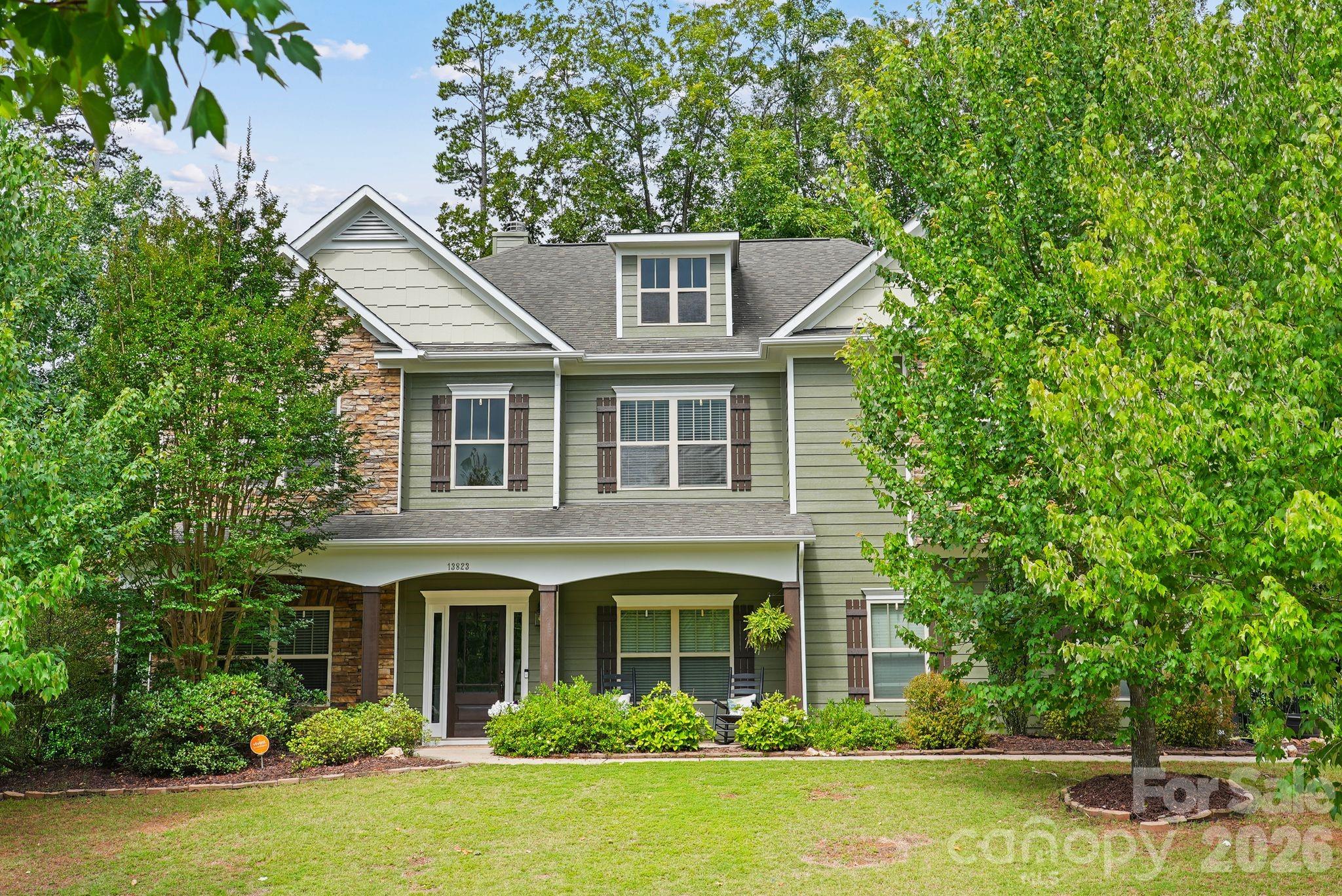 Welcome to 13823 Lawther Road, a two-story home in the Mirabella community. A covered front porch welcomes you inside, where hardwood flooring extends throughout much of the main level. The thoughtfully designed kitchen features granite countertops, a walk-in pantry, double wall ovens, a gas cooktop, stainless steel appliances, a coffee bar, and ample counter seating. The kitchen connects to a breakfast nook and the living room, complete with a floor-to-ceiling stone wood burning fireplace and custom built-ins.

The main level also offers flexibility with a guest bedroom featuring a walk-in closet, ideal for visitors or multigenerational living, along with a full bath, formal dining area, and a dedicated bar/entertainment room perfect for hosting gatherings.

Upstairs, the primary suite comes equipped with dual walk-in closets and an adjoining flex space that can be tailored to your needs as a home office, fitness area, nursery, or sitting room. The en-suite bath features a double vanity, soaking tub, and walk-in shower. A versatile family room provides additional living space, while two secondary bedrooms, a full bath, and a conveniently located laundry room complete the upper level.

Step outside to enjoy the fully fenced backyard, situated on a partially wooded lot and thoughtfully designed for both relaxation and entertaining. The outdoor living space features a patio, fire pit, and storage shed, offering plenty of room to gather, play, or unwind. Adding to the home's appeal, the front of the property overlooks open green space, creating a peaceful setting to relax on the front porch. A side-load garage and extended driveway offer additional curb appeal and functionality, complete with an in-ground basketball hoop for recreation. Recent updates include a new Trane HVAC system and furnace installed in 2024, along with a fresh exterior paint and siding refresh completed in 2026.

Residents of Mirabella enjoy neighborhood amenities including a community pool and playground, all within minutes of Birkdale Village, Lake Norman, Blythe Landing, and Discovery Place Kids. With easy access to shopping, dining, parks, and waterfront recreation, Mirabella offers the perfect blend of convenience, lifestyle, and neighborhood charm.