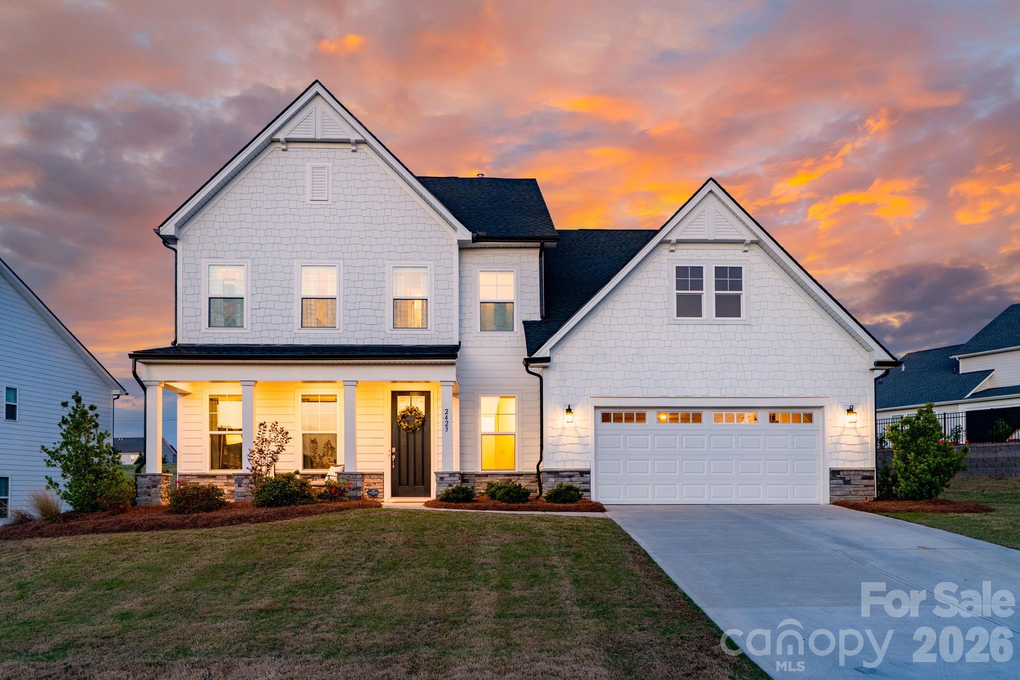 Exquisite, meticulously maintained modern farmhouse offering 5 bedrooms and 4.5 baths. Built in 2024 by Toll Brothers, this exceptional home is nestled in Fort Mill’s coveted Ridgecrest community, just moments from Charlotte's Ballantyne Area with premier shopping, dining, entertainment, and effortless access to major highways. A thoughtfully curated open-concept design blends sophistication and functionality, featuring a main-level guest suite and a private home office with custom glass doors. The great room is anchored by a gas fireplace with custom built-ins and designer lighting, creating a warm yet refined gathering space. The gourmet chef’s kitchen impresses with an expansive island, high-end appliances, hooded gas cooktop with pot-filler, stacked cabinetry, and a spacious walk-in pantry, complemented by a convenient drop zone and powder room. Seamless indoor-outdoor living awaits with a covered patio showcasing a striking stacked-stone gas fireplace and motorized screen, extending to an enlarged patio overlooking the professionally landscaped, fenced backyard—perfect for both intimate evenings and upscale entertaining. Upstairs, the luxurious primary suite is gorgeous and a true retreat, highlighted by a tray ceiling and a spa-inspired bath featuring two expansive walk-in closets, a freestanding soaking tub, oversized glass-enclosed tiled shower, and dual vanities. Three additional bedrooms, two full baths, a generous loft, and a beautifully appointed laundry room with built-in cabinetry, countertops, and utility sink complete the upper level. Set within a low-tax area and served by highly regarded schools, this home offers an exceptional blend of elegance, comfort, and convenience.