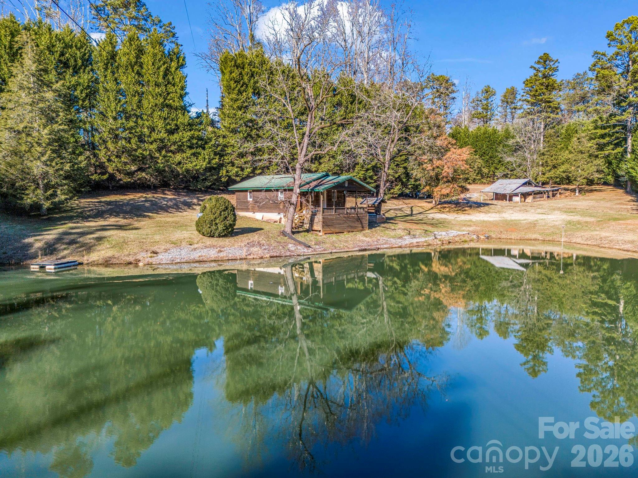 Escape to your own private mountain retreat! Nestled on 3.83 peaceful acres, this charming cabin overlooks a beautiful spring-fed, stocked pond, creating the perfect setting to relax and reconnect with nature. Offering both privacy and convenience, this unique property is ideal as a weekend getaway, full-time residence, or investment opportunity. The cozy 1-bedroom, (no closet) 1-bath cabin features an eat-in kitchen with ample cabinetry, appliances replaced in 2020, and an open-concept living area. In the summer of 2026, the seller completed several valuable improvements, including new electrical service with a 200-amp meter base and whole-house surge protection, installed new water line, removed popcorn ceilings and applied fresh paint throughout the ceilings. From the living room, step onto the covered front porch to enjoy tranquil pond views, abundant wildlife, and hours of peaceful outdoor living. The spring-fed pond is stocked with a variety of fish, making it a favorite spot for anglers and nature enthusiasts alike. An old barn offers endless possibilities, restore it for storage, a workshop, or hobby space, or reclaim the barn wood for future projects. The property is served by a shared well with the neighboring 2-bedroom, 1-bath home, which is also available for purchase (see MLS #4379535). Purchase both properties to create a private family compound or expand your investment portfolio with two rental opportunities. Conveniently located less than an hour from three major airports, the property is just minutes from downtown Columbus for shopping, dining, and easy access to I-26 and US-74. Enjoy exploring the nearby towns of Tryon, Landrum, Saluda, and Lake Lure, along with countless opportunities for hiking, camping, fishing, cycling, and other outdoor recreation. The area is known for its scenic roads and light traffic, making it especially popular with cyclists. The Tryon International Equestrian Center is only about 10 minutes away and offers world-class equestrian events, sporting competitions, concerts, dining, shopping, and year-round entertainment. Whether you're seeking a year-round home, private getaway, or an investment opportunity, this property has much to offer, so don't wait!