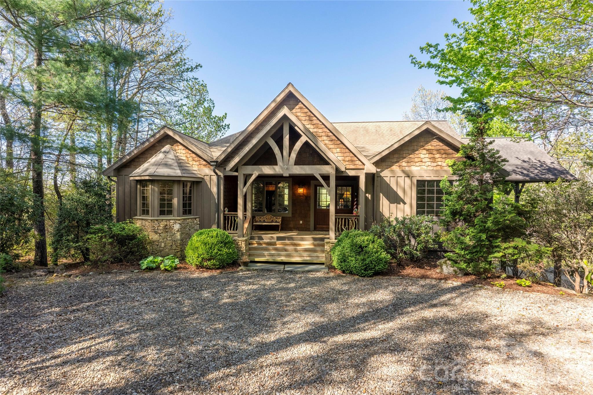 A private mountain estate property nestled on Hawk Mountain with over 2 acres of sweeping views of Lake Toxaway and the surrounding mountains. Inside, the home is warm and inviting, centered around a stunning great room with a stone fireplace, a chef’s kitchen, and a dining area highlighted by rich wood architectural details. These spaces flow seamlessly onto an expansive covered deck designed for entertaining, complete with a barbecue area, lounge seating, and an outdoor fireplace. In addition to the charming main level, a lower level offers a spacious media and game room and three additional bedrooms. The grounds are just as impressive, featuring lush perennial gardens, terraced stone landscaping, and ample guest parking. There is so much to enjoy in this peaceful mountain retreat.