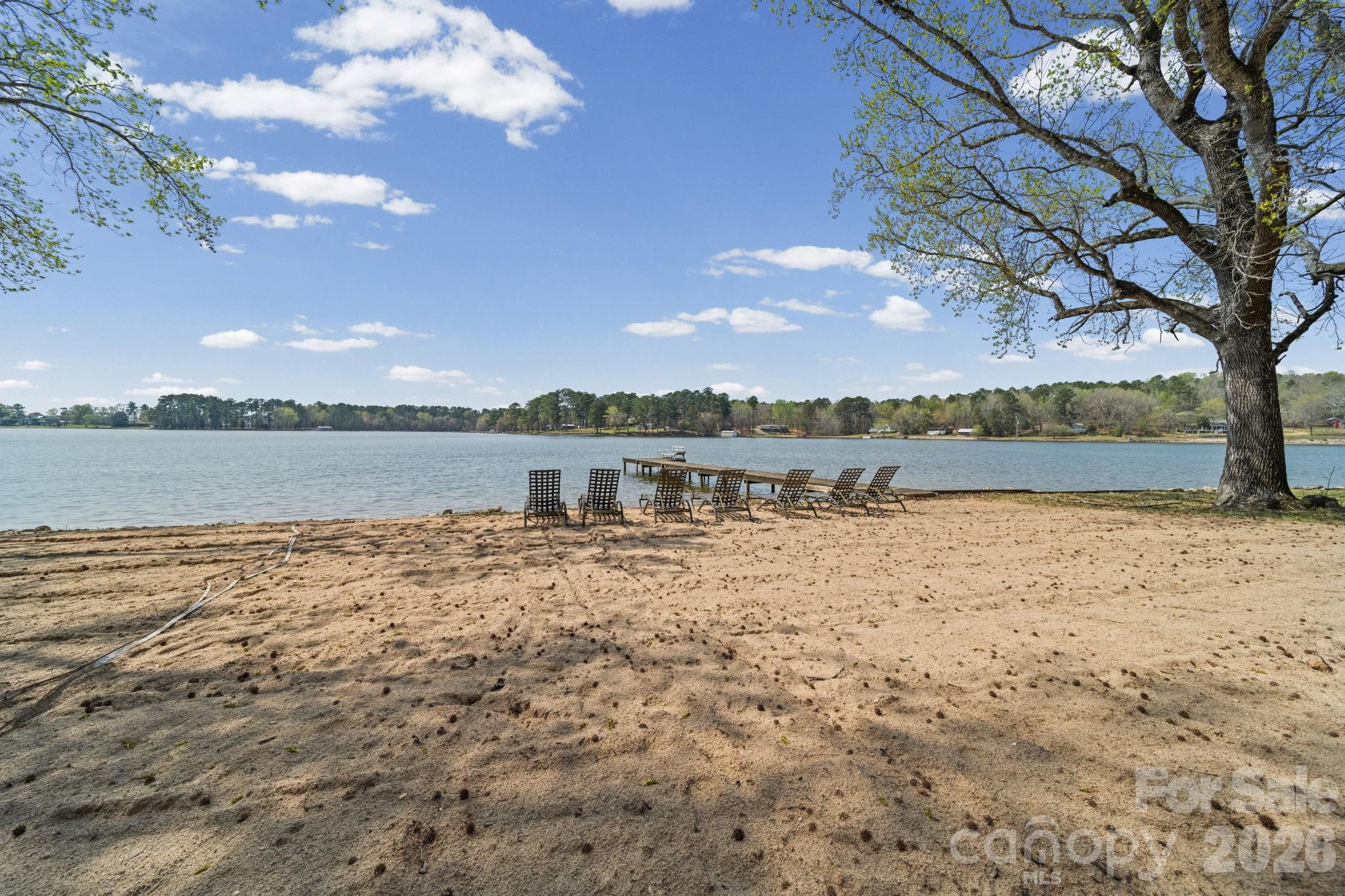 Recently remodeled and relaunched with a newly constructed second bedroom! Now offering a true 2-bedroom layout, this beautifully updated lakefront retreat combines premium finishes, stunning water views, a rare double lot, and an oversized workshop/garage with a half bath. With additional living and sleeping areas that could easily be adapted into more private bedroom space, this property offers a level of flexibility rarely found in lakefront homes. The bright and inviting interior features exposed beams, tile flooring, and an open-concept kitchen with island and pantry, designed for effortless entertaining. Multiple gathering spaces throughout the home provide the perfect place to relax, host family and friends, and take in the breathtaking lake views from both levels. Outside, enjoy your own sandy beachfront, private pier with ladder, volleyball area and unforgettable sunset views. Spend your days swimming, boating, fishing or simply enjoying the peaceful waterfront setting. A standout feature of the property is the oversized workshop/garage with attached carport, half bath, water, electric, and its own independent septic system already in place. With exceptional storage for boats, side-by-sides, and water toys, plus future potential limited only by your imagination. This space is a rare find on the lake. Whether you’re searching for a full-time residence, a weekend getaway, or an investment property, this move-in-ready waterfront escape offers the lake lifestyle you’ve been dreaming of.