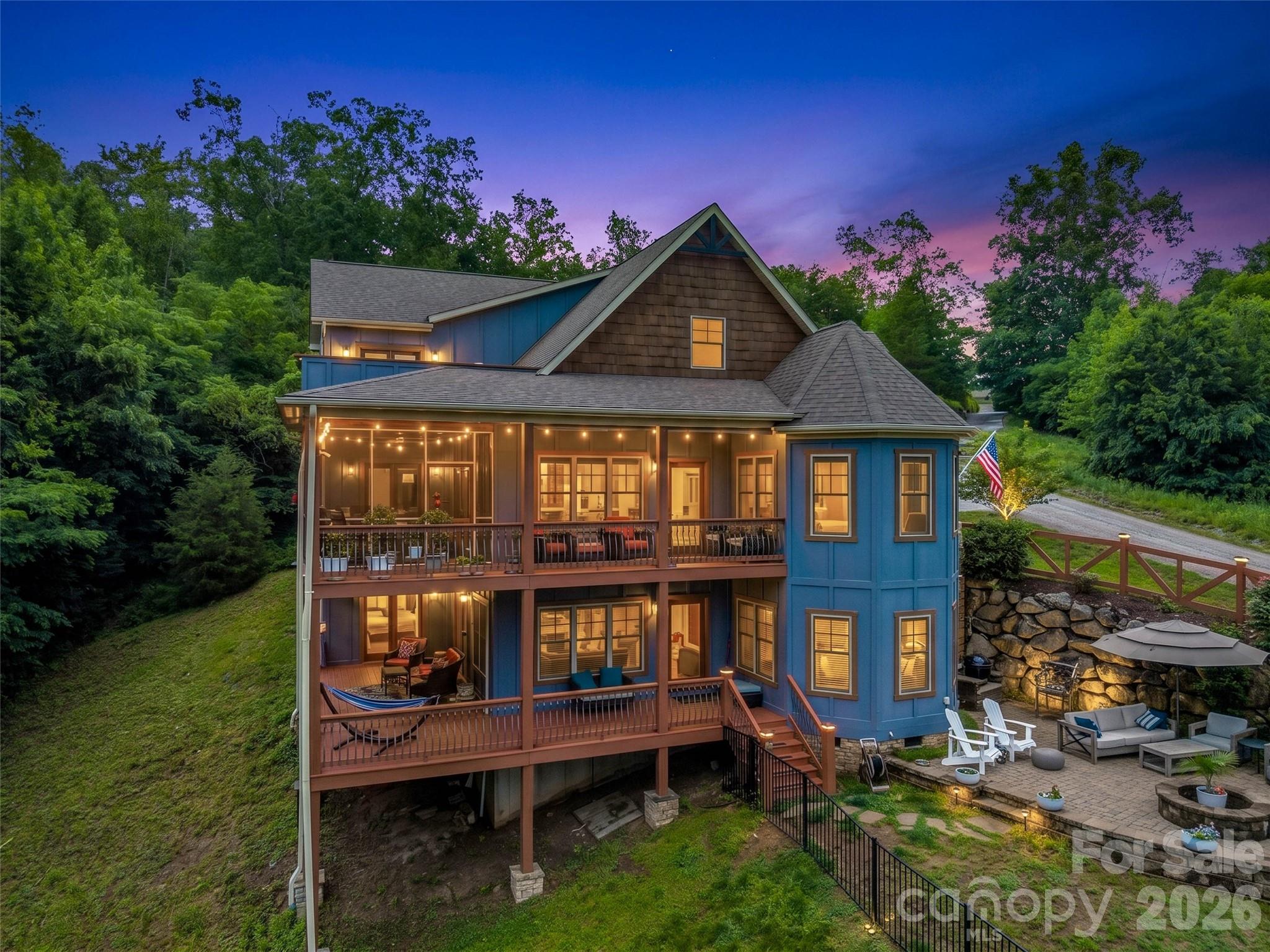 Where panoramic mountain views meet the feel of a private rainforest retreat, this one-of-a-kind custom home creates an experience unlike anything else on the market. Positioned at the very end of a quiet cul-de-sac inside the gated Vista at Bill’s Mountain community, the property is surrounded by protected natural beauty, with a rushing mountain stream and walking trail just beyond the backyard. From sunrise over the long-range mountain views to evenings spent listening to the sounds of the creek from your deck, every space was designed to connect you with nature while still offering refined luxury and comfort. Expansive windows flood the home with natural light, soaring ceilings create an impressive sense of scale, and the open-concept layout flows effortlessly for entertaining or everyday living. The heart of the home is anchored by a dramatic stone fireplace that seamlessly connects indoor and outdoor living areas, while the chef’s kitchen offers premium stainless appliances, generous gathering space, and easy access to multiple outdoor decks. The main-level primary suite provides a peaceful escape with direct access to the outdoor living spaces, creating the perfect place to unwind after a day in the mountains. The lower levels offer incredible flexibility with spacious recreation areas, guest accommodations, and bonus rooms ideal for additional sleeping quarters, office space, or hobby rooms. With no homes beyond your view line and fewer than 100 homes throughout this 800-acre gated community, privacy here feels truly unmatched. This is not simply a mountain home—it’s a secluded sanctuary where luxury and nature exist in perfect balance.