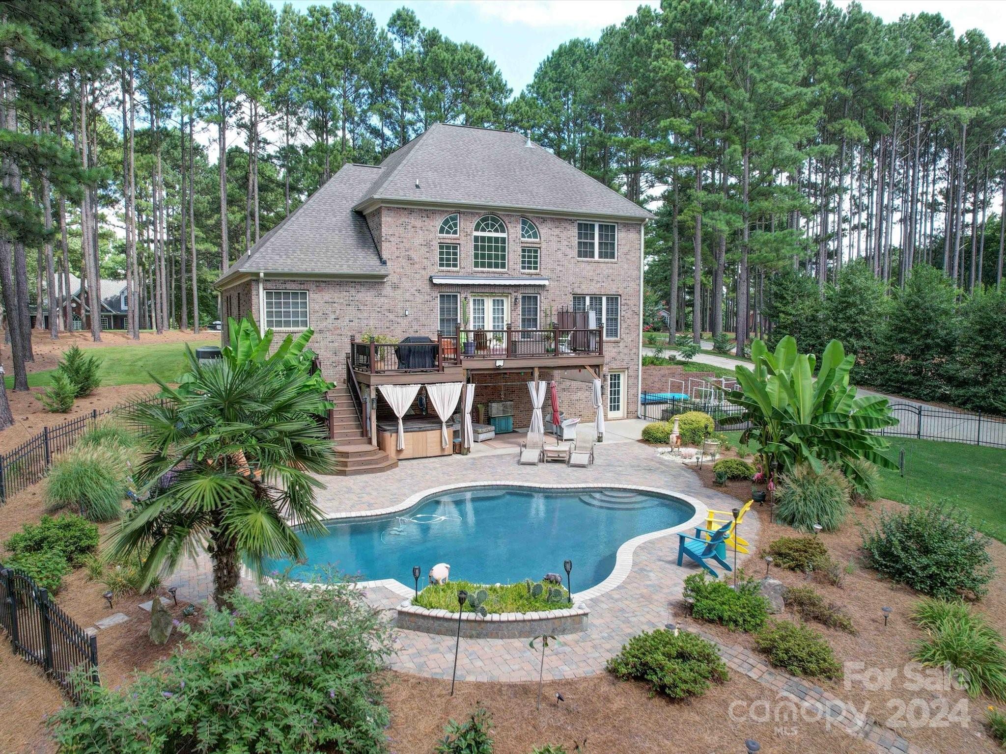 Welcome to your private oasis! All brick 4 bedroom home. The lot is wooded and provides access to Lake Wylie with a waterfront to a cove. While it is not dockable, it is suitable for launching canoes, kayaks, or possibly a jet ski. The backyard has a retreat-like atmosphere, with an inground saltwater pool, a hot tub, and a large Trex deck, offering a relaxing setting. Inside the home features includes a beautiful chef's kitchen with designer cabinets and granite countertops, a primary suite on the main floor with a space for an office or sitting area, and terrific views of the backyard from the windows. Hardwood floors are on the main level. Storage galore underneath the house with a 3rd door garage. *Community amenities* There is a community boat storage lot available and also a community pool.