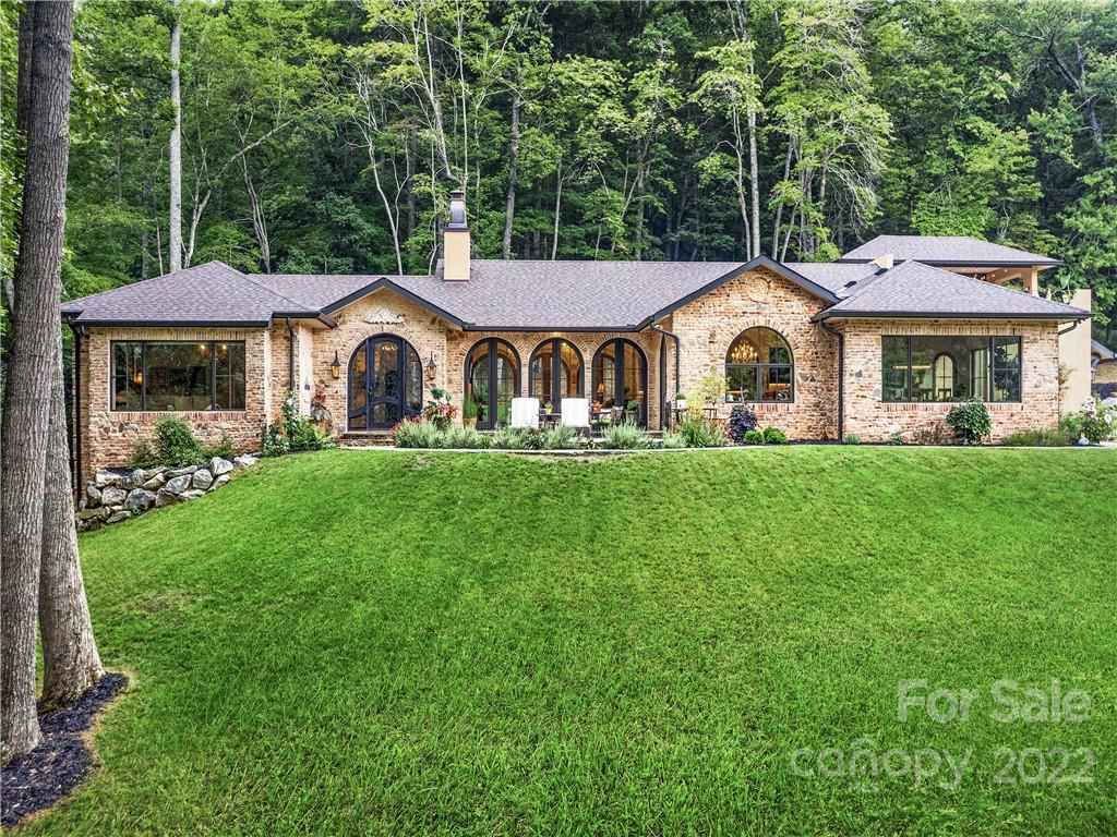 Within 16+ very private acres, you will find a sophisticated villa with extraordinary finishes. This custom-built, one-level home offers modern convenience and elegant living at its finest. Unwind under the canopy of hand-crafted barrel and groin ceilings and stunning Swarovski crystal chandeliers. A beautifully appointed kitchen boasts an expansive quartzite island, hammered copper sinks, and sleek stainless steel appliances. Entertain in the wine room and generous dining room with gorgeous mountain views and space for gatherings both large and small. The spa-inspired primary bath invites you to relax in the hammered copper slipper tub or private outdoor shower. Wireless Control 4 smart home system manages lighting, audio, thermostats, & security including cameras all from your phone. Property includes an historic log cabin, barn with pastures, flagstone patios, firepit, and hot tub deck. A hidden oasis directly bordering Pisgah National Forest for hiking, biking and horseback riding.