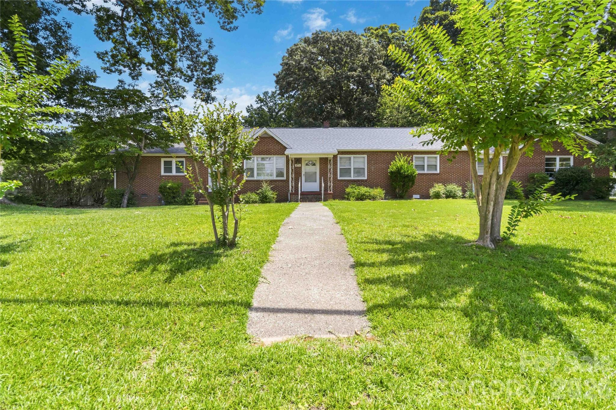 Discover the charm of small-town living in this all-brick ranch located in the heart of Sharon, South Carolina. Situated on approximately 0.69 acres, this property is surrounded by mature trees that provide shade and a peaceful setting. Inside, you'll find three bedrooms, three full bathrooms, original hardwood floors, a formal living room, and a spacious den offering flexible living space. The large kitchen provides ample cabinet and counter space and is complemented by a formal dining room, making it ideal for everyday living and entertaining.
Outside, enjoy both an attached two-car garage and a detached two-car garage, plus multiple storage buildings that provide excellent space for hobbies, projects, or additional storage. A circular driveway enhances convenience and curb appeal. The roof was replaced in approximately 2021, and the HVAC system has also been updated. Don't miss the opportunity to own this well-maintained home and experience the charm and convenience of life in Sharon.