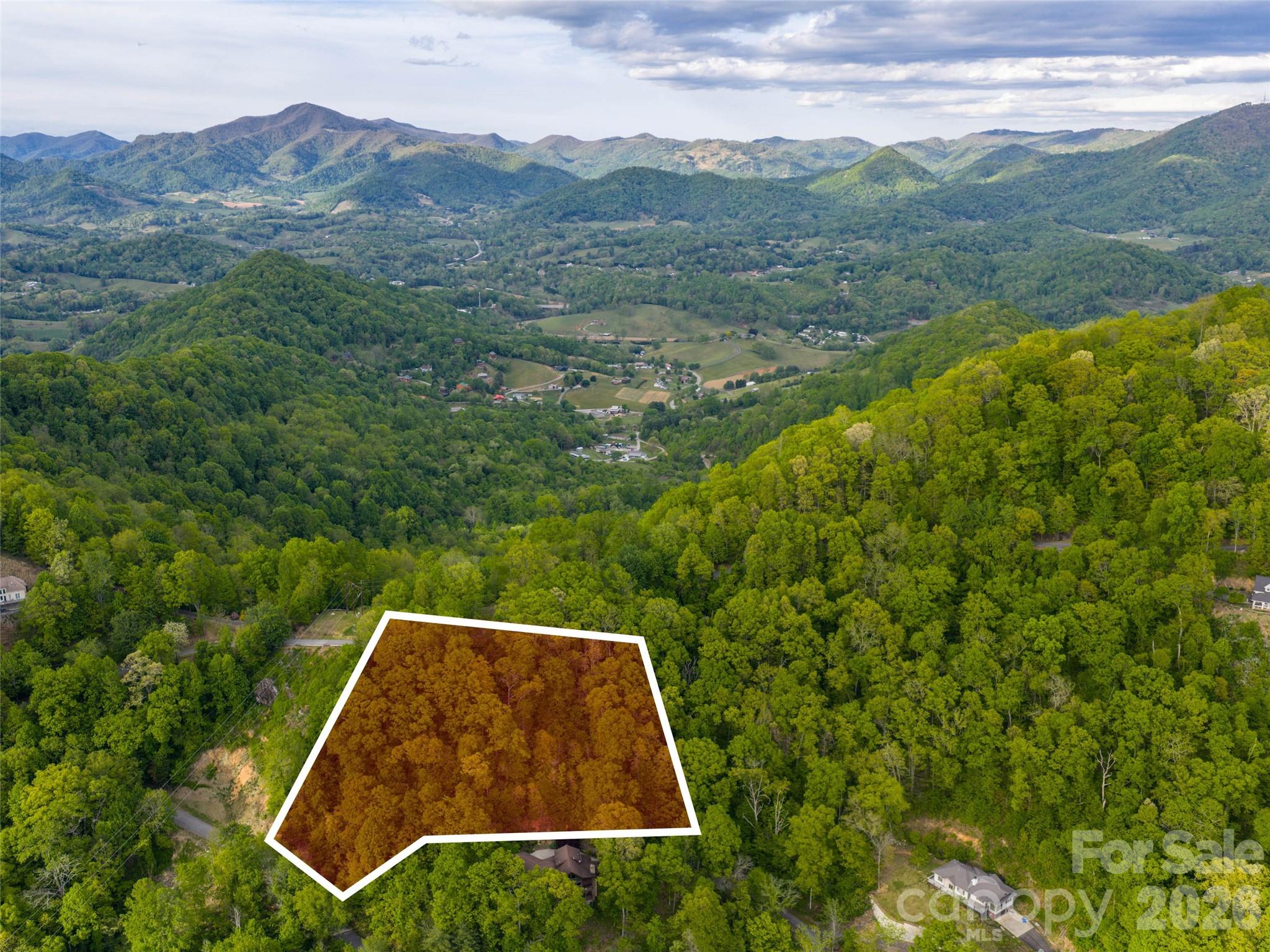 Discover the perfect canvas for your mountain dream home on this stunning 3+ acre lot in the highly sought-after Junaluska Highlands, a prestigious gated community nestled in the heart of Western North Carolina’s Blue Ridge Mountains. Offering breathtaking long-range mountain views that stretch across rolling ridges and misty valleys, this wooded parcel is ideally positioned with a gentle southern exposure—perfect for maximizing natural sunlight, passive solar benefits, and year-round scenic enjoyment. Mature hardwoods and native flora frame the property, providing privacy and a serene, natural setting while allowing you to selectively trim for even more dramatic vistas. Wide, paved roads with gentle access lead directly to the site, and underground utilities ensure a clean, uncluttered build. City water and Spectrum high-speed internet are already available, Septic system needed, simplifying construction and modern living. Junaluska Highlands is known for its beautiful custom homes and peaceful, upscale atmosphere, where neighbors value quality and tranquility. Just minutes from charming downtown Waynesville, you’ll enjoy boutique shops, farm-to-table restaurants, breweries, and vibrant community events. Asheville’s dynamic arts scene, airport, and world-class amenities are only 25 minutes away, while Maggie Valley and the Great Smoky Mountains National Park are within easy reach for hiking, skiing, and outdoor adventures. This rare opportunity combines privacy, convenience, and unparalleled natural beauty. Whether you envision a luxurious primary residence or a scenic mountain getaway, this lot delivers the foundation for a lifetime of inspiration. Don’t miss your chance to claim this slice of North Carolina mountain paradise.