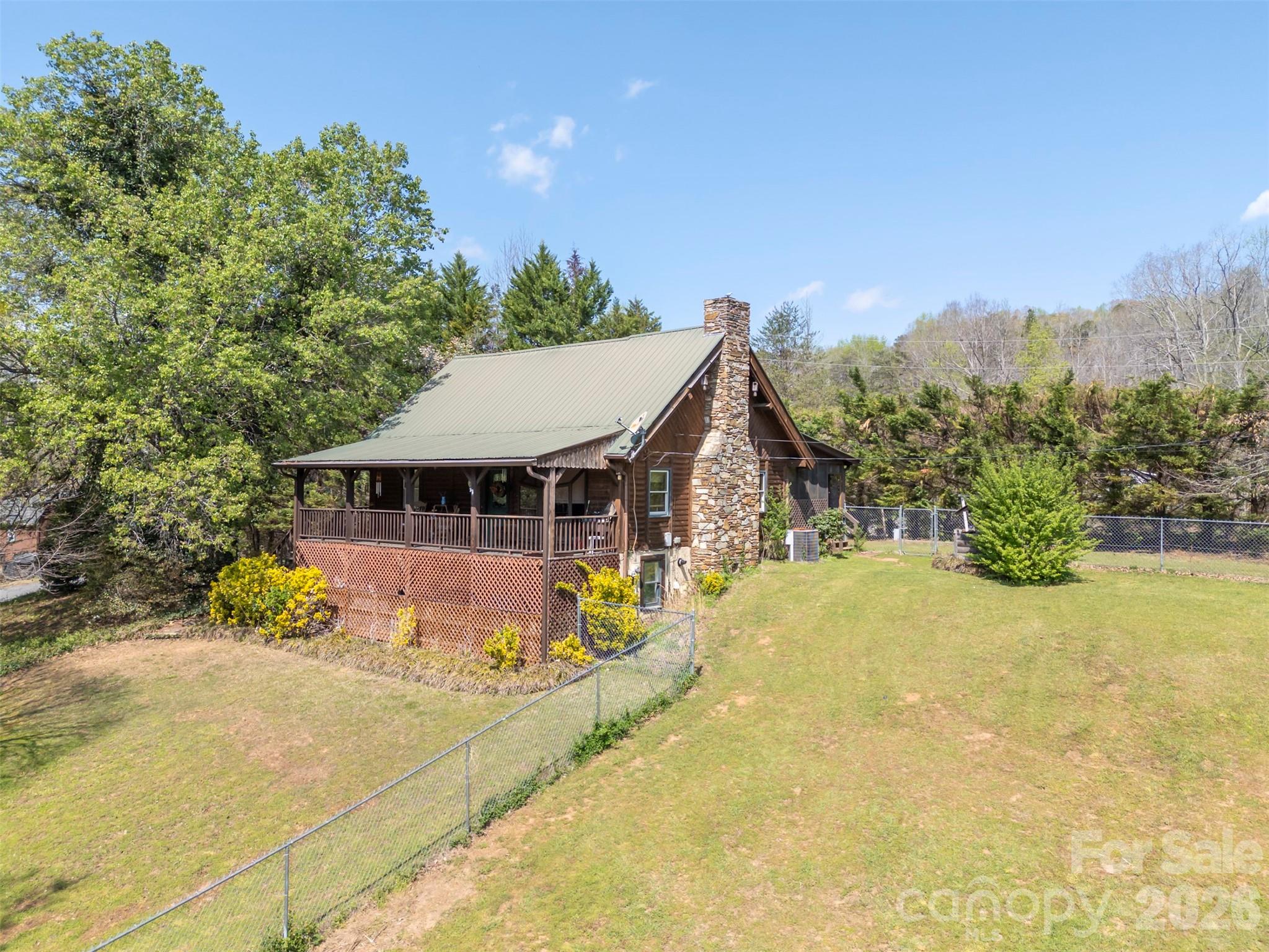 Tucked away on 1.22 peaceful acres between Rutherfordton and Lake Lure, this charming 3-bedroom, 2-bath cabin offers the perfect blend of rustic character and modern comfort. When you step inside, you'll find beautiful hardwood floors, vaulted ceilings, and custom woodworking accents that create a warm, inviting atmosphere. The cozy gas log fireplace makes the living space ideal for relaxing evenings at home and a tankless water heater adds efficiency and convenience. Enjoy the outdoors from both the covered front porch overlooking the fenced yard and the screened-in back porch—perfect for taking in the serene surroundings year-round. Need extra space? The 16x20 outbuilding with power is ideal for hobbies, a workshop, or additional storage, and is complemented by an attached carport and rear lean-to for even more functionality. An exterior entry unfinished basement provides excellent storage options, and the private setting offers a quiet retreat while still being conveniently located between Rutherfordton and Lake Lure. Whether you're looking for a full-time residence or a weekend getaway, this property delivers comfort, charm, and versatility in a beautiful natural setting!