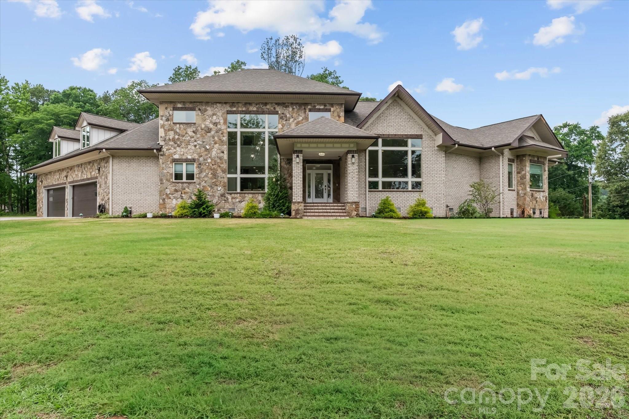 This exceptional custom-built luxury home, originally crafted as a builder’s personal residence, is a true showcase of timeless elegance, superior craftsmanship, and thoughtful design. 
Perfectly perched just across the street from Lake Norman, the home offers an unmatched blend of sophistication, functionality and privacy.
Step through the stunning leaded glass front door into a light-filled interior where soaring ceilings and expansive windows frame breathtaking water views from nearly every room. The impressive Great Room features a dramatic cathedral ceiling and a floor-to-ceiling stone fireplace, creating a warm yet grand gathering space filled with natural light throughout the day.
Designed for both easy every day living as well as entertaining, the gourmet chef’s kitchen is equipped with top-of-the-line stainless steel appliances, two ovens (one electric and one steam oven), wine refrigerator, gorgeous granite countertops, a massive center island (with additional storage below), and a generously sized walk-in pantry.
Luxury design elements continue throughout the home with beautifully appointed bathrooms featuring custom inlaid tile work, and abundant closet space with an incredibly unique “retail display” style of hanging storage (even has a urinal!).  The private, flat .87-acre lot (pool approved) provides exceptional space to garden or kick around a soccer ball between the World Cup games this summer. Or, you can sit outside under the ceiling fans on the shady porch and daydream about exactly how you would design your own pool & outdoor living space.
Whether you’re a bonafide automobile lover or just someone with plenty of recreational toys that need their own space, you will most certainly appreciate the convenience of a rare attached 4-car garage!  There is even additional parking around the back of the property for an RV or boat. And, NO HOA!
