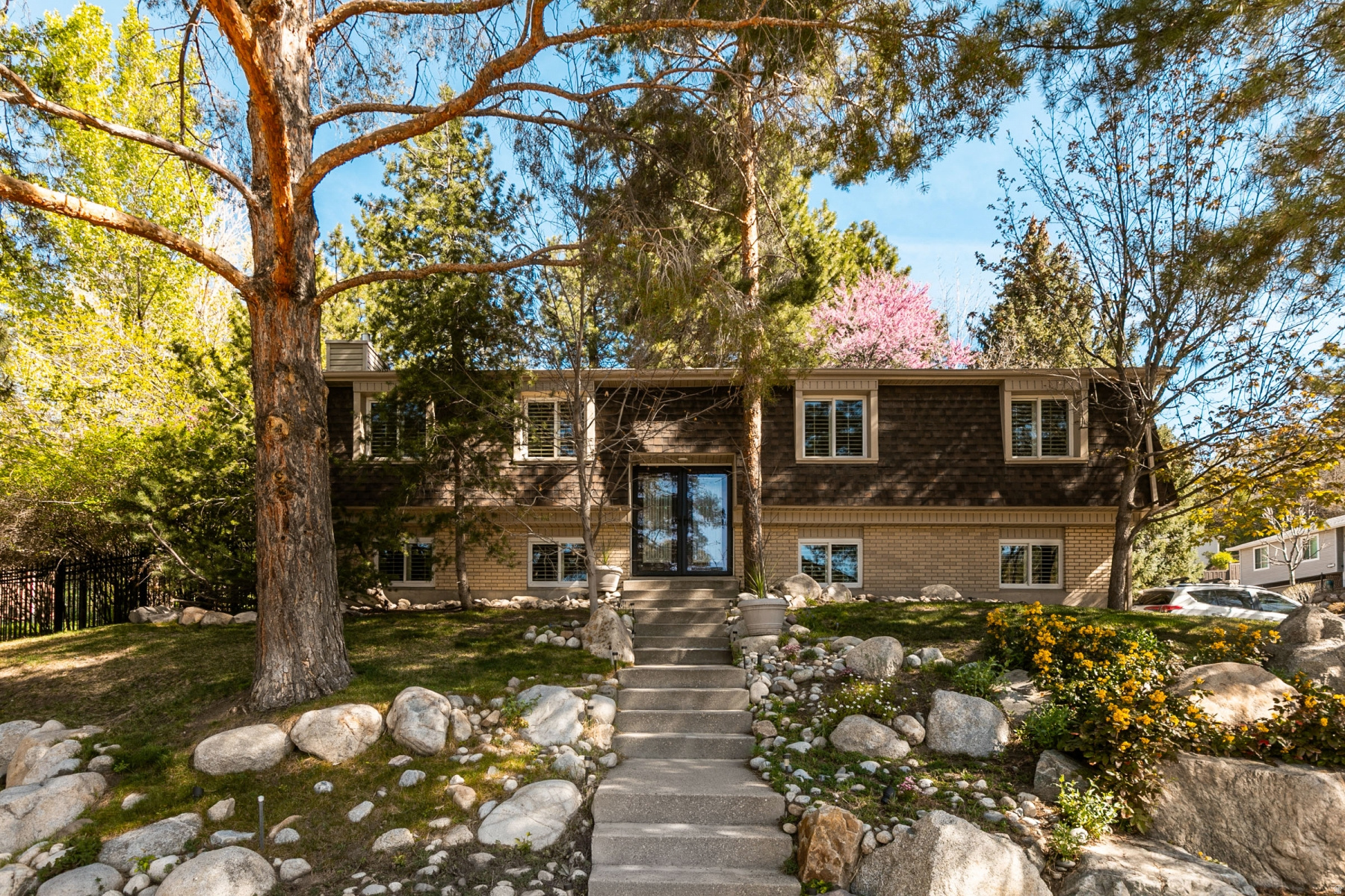 Experience mountain living at its finest in this "Chalet in the Pines!" This 2021 renovation is impeccably clean and move-in ready. The chefs kitchen boasts a quartz island and buffet, induction range, and new fridge. Relax in the spa-like primary bath featuring a rain shower or enjoy the open-concept living area with custom built-in cabinets and premium Pella windows/doors with plantation shutters. The private, resort-style backyard is a sanctuary, featuring a custom stone patio, hot tub, and local landscape boulders nestled among the pines. Located in a prime Cottonwood Heights neighborhood near both Cottonwood Canyons, this freshly painted gem offers an opportunity to own a high quality and unique home in a special community.