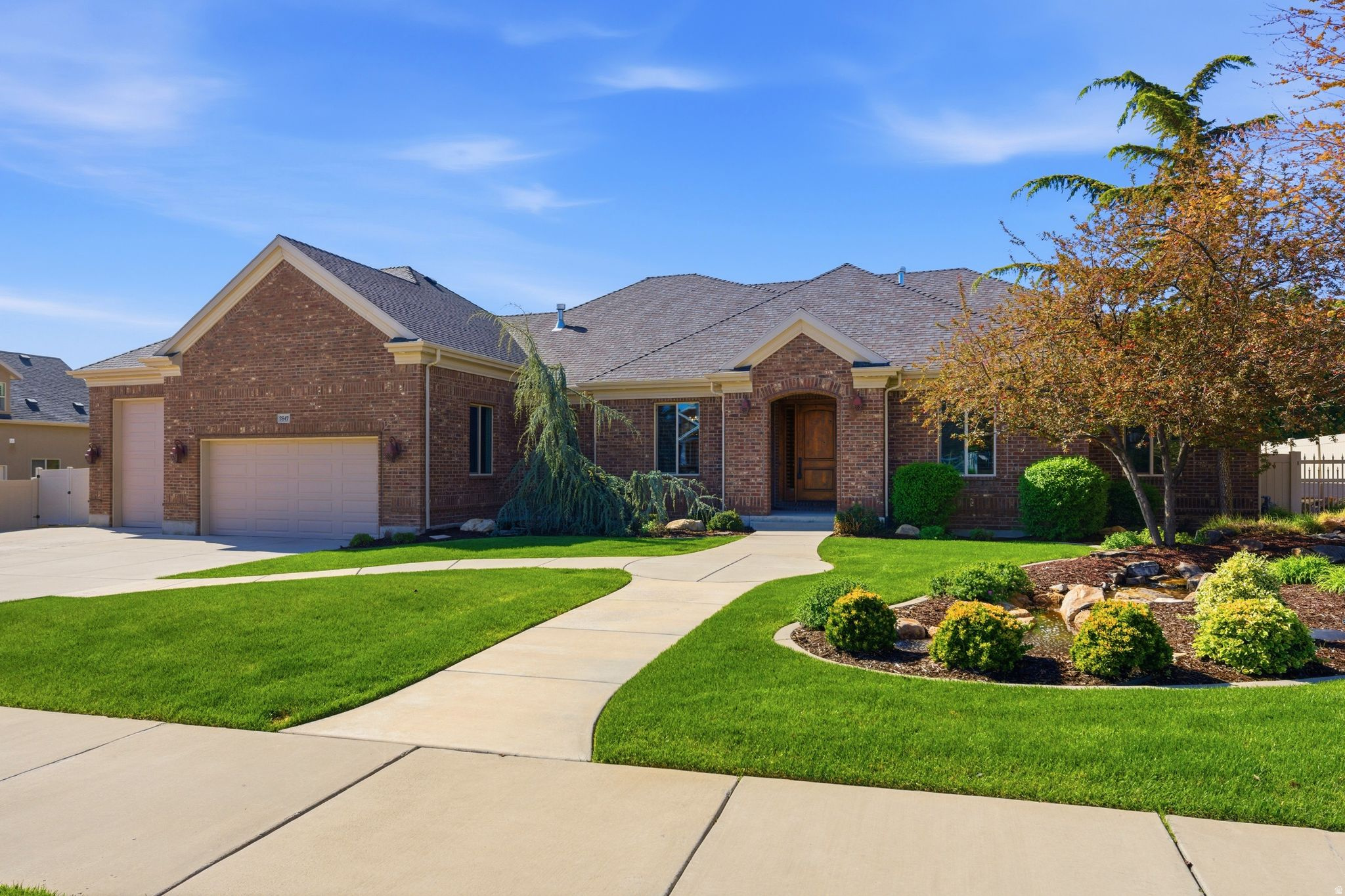 WOW! What a find! This is your opportunity to own a beautifully updated custom rambler in one of South Jordan's most sought-after neighborhoods. From the moment you arrive, the professionally designed landscaping and tranquil water feature with a flowing stream create a true sense of arrival and serenity that sets this home apart. Step inside and be welcomed by an open, light-filled floor plan featuring vaulted ceilings, expansive windows, 8-foot solid alder doors, and a stunning stone fireplace. This home showcases exceptional craftsmanship and timeless design, perfectly suited for both everyday living and elevated entertaining. The chef's kitchen is a true centerpiece, offering a substantial island, extensive custom cabinetry, a copper sink, a generous walk-in pantry, and premium Wolf appliances-seamlessly blending luxury and functionality. The spacious primary suite serves as a private retreat, featuring a jetted tub, walk-in shower, and two large closets, along with direct access to the peaceful, secluded backyard. The fully finished basement offers 9-foot ceilings, a full second kitchen, and a private walkout entrance, providing ideal flexibility for multi-generational living, guest accommodations, or ADU potential. Car collectors and outdoor enthusiasts will appreciate the oversized 4-car garage, including a dedicated RV bay with an oversized door, gas lines plumbed for heaters, and ample vertical space for storage, recreation, or workshop use. Additional RV parking further enhances versatility. Step outside to your own private backyard sanctuary, thoughtfully designed with two gazebos, hot tub readiness, and a second water feature that enhances the peaceful, resort-like atmosphere. This is a rare combination of luxury, space, craftsmanship, and location-all within walking distance to schools, shopping, and dining in a highly desirable community. This gem won't last so, Come and See!