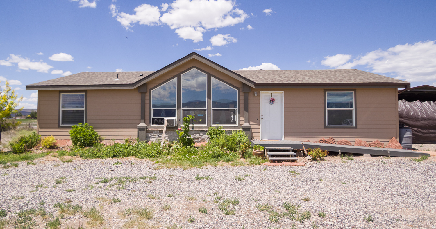 Your Private Retreat in the Heart of Wayne County! Welcome home to a place where every day feels like a getaway. Nestled in a peaceful farming community surrounded by stunning mountain views and abundant outdoor recreation, this custom-built home offers the perfect blend of comfort, functionality, and country charm. Conveniently located near Capitol Reef National Park and Fish Lake, you'll enjoy easy access to hiking, fishing, ATV trails, hunting, and year-round adventure. Designed with accessibility in mind, this FHA-approved home features spacious 36-inch doorways, large windows that fill the home with natural light, and soaring cathedral ceilings that create an open, inviting atmosphere. Gather around the cozy wood-burning cooktop fireplace or unwind after a day of exploring relax beneath the stars in the newer hot tub while enjoying the peace and beauty of Wayne County's dark skies. The thoughtfully designed kitchen showcases beautiful custom wood cabinetry with crown molding, a ceramic subway tile backsplash, self-closing drawers, adjustable shelving, dedicated pot-and-pan storage, rolling trash bins, and abundant pantry space. Quality finishes throughout include 4-inch baseboards, walk-in closets, and ample storage. Outside, you'll discover a lifestyle many only dream about. Enjoy mature fruit trees, berry patches, a greenhouse, chicken coop, gazebo, covered carport, and plenty of room to garden, relax, and enjoy the peaceful surroundings. Whether you're seeking a primary residence, peaceful retirement retreat, weekend escape,  hobby farm, vacation retreat, or investment opportunity, this property offers the perfect balance of rural living and modern comfort. Buyer to verify all information. Information deemed reliable but not guaranteed.Square footage figures are provided as a courtesy estimate only and were obtained from county records .  Buyer is advised to obtain an independent measurement.