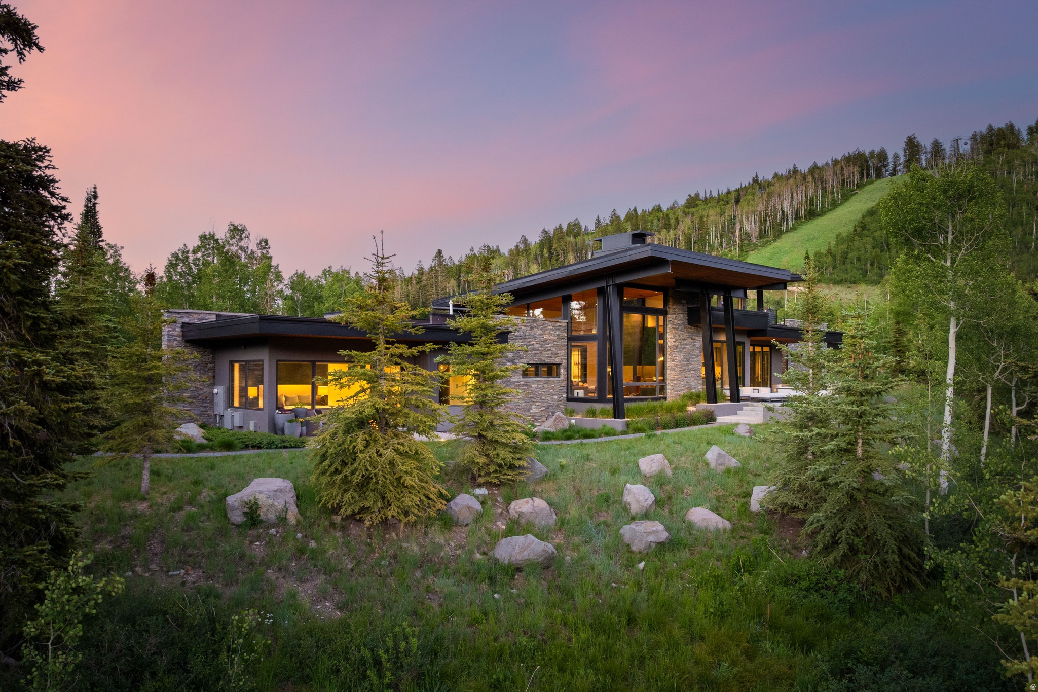 Perched on one of the finest homesites in The Colony, this exceptional residence enjoys a rare, flat homesite in one of Park City's most coveted ski-in/ski-out communities. Artisan-modern architecture blends seamlessly with the surrounding landscape, offering remarkable privacy, tranquility, and panoramic mountain views. Designed with both sophistication and adventure in mind, the home features soaring ceilings, walls of glass, and a refined palette of natural wood, stone, steel, and custom millwork. Expansive living spaces flow effortlessly to outdoor terraces with fire pits and hot tubs, creating an ideal setting for entertaining or relaxing beneath the stars. The gourmet kitchen, complemented by a fully equipped butler's kitchen, is outfitted with premium appliances and custom cabinetry. The main-level primary suite is a private retreat with spa-inspired baths, generous walk-in closets, and inspiring mountain views. Above it all, the spectacular 1,800-square-foot rooftop deck captures breathtaking vistas in every direction. For those seeking premier ski access, exceptional views, abundant natural light, and a more manageable luxury estate, this home offers an unparalleled opportunity. Enjoy world-class skiing in winter, hiking and mountain biking from your doorstep in summer, and Historic Main Street just minutes away. Owners will also enjoy The Colony's highly anticipated community clubhouse, opening later this year, with exclusive dining and gathering spaces that further elevate this extraordinary mountain lifestyle.