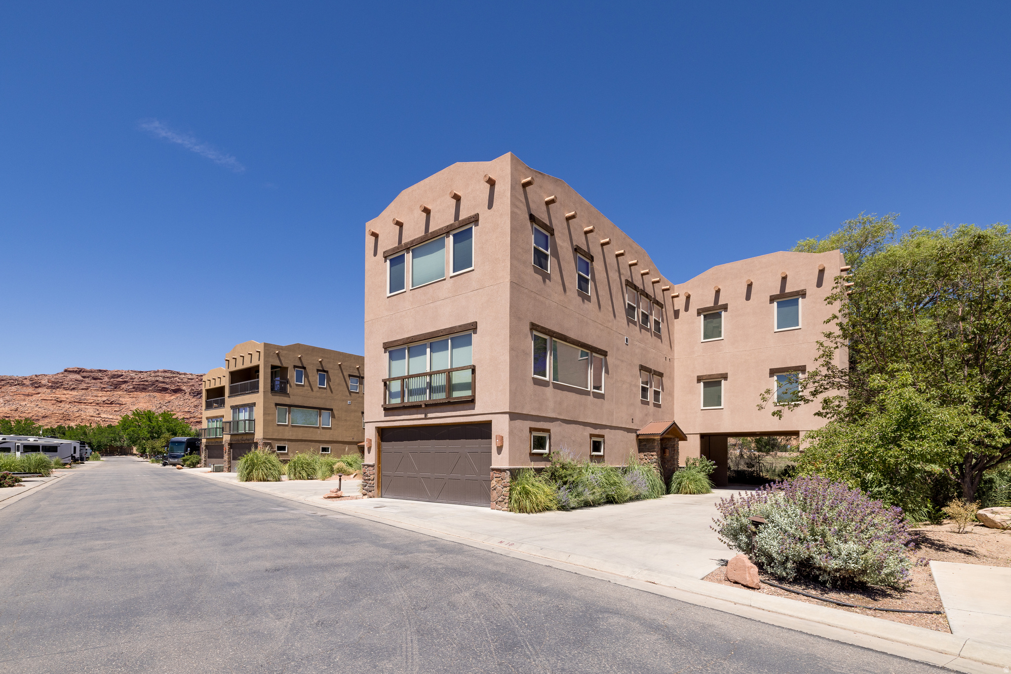 BUILT FOR GATHERING AND ADVENTURE - Set against the backdrop of the Colorado River Portal, this beautifully furnished home in Village Camp Resort offers the space, comfort, and resort amenities to enjoy Moab at its best. This amazing furnished home has over 3,100 sf and is comprised of three levels with fabulously designed living spaces.  The first level offers a foyer, double covered patio, and 2 car garage. At the heart of the home on the second level, the open-concept living area flows effortlessly into a well-appointed kitchen featuring granite countertops, stainless steel appliances, abundant cabinetry, generous breakfast bar seating, and pantry with laundry. This floor includes an en-suite bedroom, and a spacious theater room with half bath. The quality continues onto the third floor with three spacious bedrooms, each offering its own private bathroom, as well as an additional laundry facility. Currently operating as a short-term rental, this turnkey property is being offered fully furnished, including furniture, dcor, electronics, and housewares, providing an exceptional opportunity for both personal enjoyment and investment. Outside, a large covered entertaining area invites everything from casual mornings with coffee to evenings spent enjoying Moab's spectacular sunsets. Easy-care desert landscaping and a mature shade tree create an outdoor setting that is both beautiful and low maintenance. Village Camp Resort amenities include swimming pools, pickleball courts, a clubhouse, and a dog park, offering a resort-style experience just minutes from Moab's renowned trails, parks, and outdoor adventures. Whether you're seeking a private retreat, a gathering place for family and friends, or supplemental income for your vacation rental, this exceptional home delivers the best of Moab living.