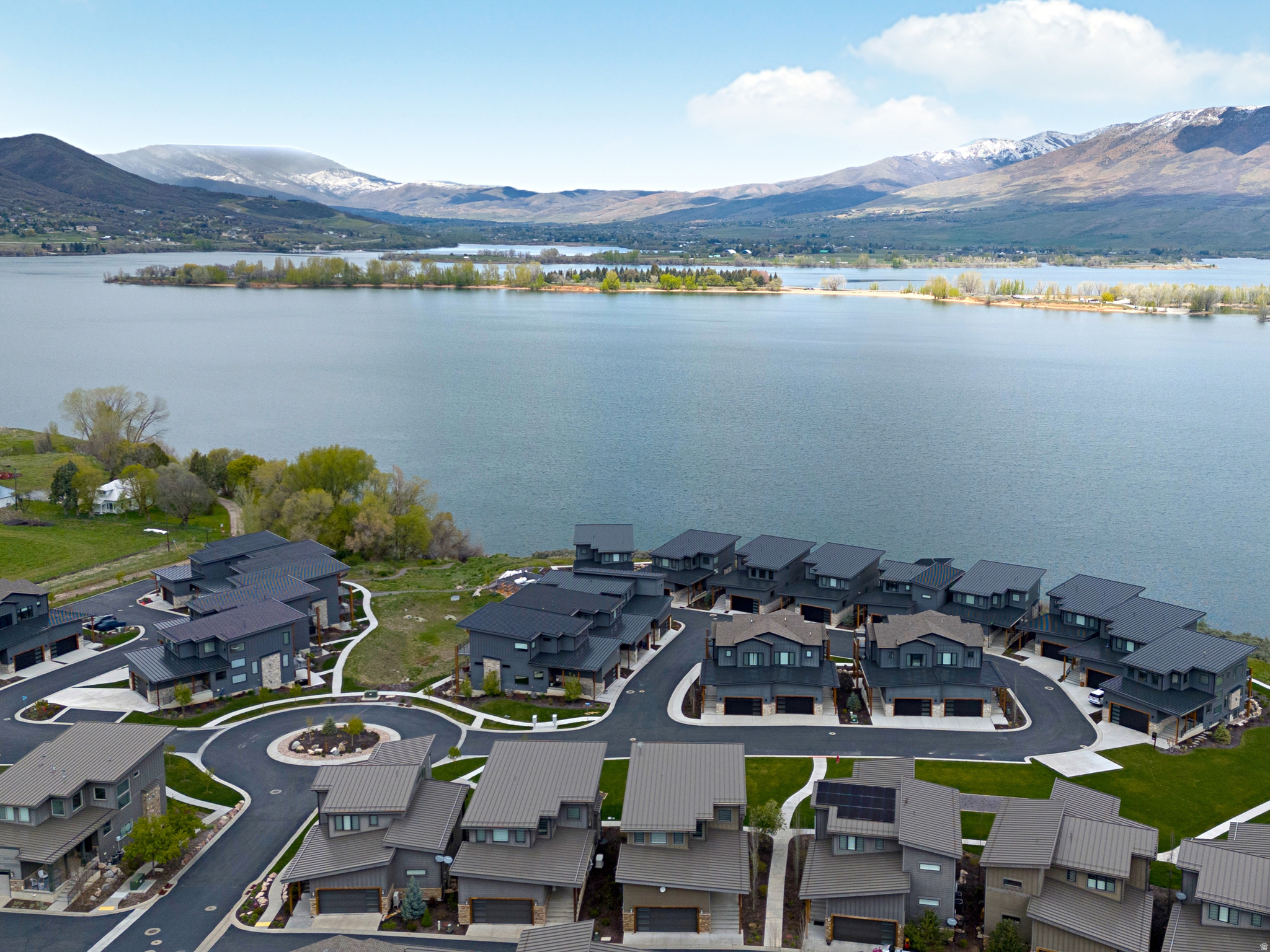SHORT TERM RENTALS ALLOWABLE MAKING THIS AN EXCEPTIONAL, TURN-KEY INVESTMENT. Extraordinary Luxury Lake Home nestled in the heart of the Wasatch Mountains and overlooking Pineview Reservoir and ONLY 8 minutes to world class skiing at Snowbasin Ski Resort, home to the 2034 Winter Olympics, and 25 minutes to Powder Mountain Ski Resort, under 1 hour to SLC and the SLC Airport. Experience the stunning lake and mountain views through expansive windows, flooding the home with natural light, seamlessly blending indoor and outdoor living. The open-concept layout features a well appointed kitchen with oversized island, ample dining space, large greatroom with inviting stone fireplace creating an inviting yet luxurious space. Sliding glass doors extend the living space to a covered deck overlooking the water to enjoy solace, evening sunsets and gathering with friends and family. Upstairs, the spacious primary suite showcases incredible panoramic views, a private deck, spa-like grand bath with elegant finishes and glass-enclosed shower. Two additional upstairs ensuite bedrooms with private baths are thoughtfully designed for comfort, privacy and style. The lower level feature, large, open family room with cozy fireplace, a wet bar, sliding doors to covered patio, private guest suite and bathroom. Well designed laundry and mudroom and finished garage. GATED community. HUGE BONUS Separate 14'X40' DETACHED GARAGE Unit S5 for sale for additional $175,000 (tax id: 20-174-0020) PERFECT for Boat or RV storage. ALSO all furniture/furnishings excluding main level couch are available for purchase.