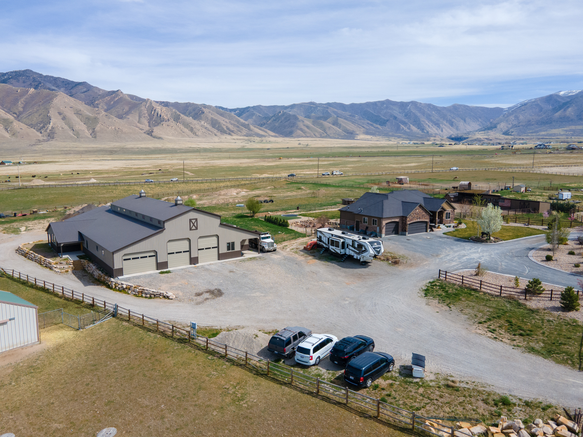 Significant Price Drop! Experience exceptional high-end country living on 4.7 acres designed for both comfort and serious functionality. This one-of-a-kind property combines a beautifully finished home with extensive outbuildings and a massive shop-perfect for hobbyists, entrepreneurs, and anyone who needs space to live, work, and entertain.  The main home welcomes you in with a custom water feature and in-laid compass in the stamped concrete walkway.  Step inside to the hand-scraped hardwood floors and a thoughtfully designed layout. The chef's kitchen features generous workspace and a walk-in pantry, ideal for cooking and hosting. A dedicated office provides a quiet workspace, while the primary suite offers a private retreat with direct walk-out access to a gazebo with a swim spa and wall mounted TV, creating a perfect spot to relax year-round.  The fully finished walk-out basement is built for entertaining and multi-generational living. Highlights include a second kitchen, mother-in-law suite, laundry room, large game area, hidden children's playroom and a stunning custom live-edge wood bar featuring a barrel from Park City Distillery, a locking sidebar dispensing unit, and a kegerator-perfect for hosting gatherings or creating a unique dirty soda or beverage bar experience.  Comfort and efficiency features include a custom security system and an attic fan to keep the home cool during spring and fall months.  The roof is a has a 50 year lifetime warranty and the windows are triple pane with lifetime replacement warranty. (Window warranty has stipulations for transferability.)   The grounds are equally impressive. The property features rebar-reinforced landscape edging around the driveway, multiple frost-free hydrants, and a productive orchard with two apple trees, two peach trees, one nectarine tree, one plum tree, one pear tree, three cherry trees, two grape vines and raspberry bushes, all on drip irrigation.   Inside the attached three-car garage, you'll find 220V power, an RV electric hookup, and an RV dump station on the north side of the garage, plus an additional RV power hookup along the north fence line. The home is equipped with permanent exterior lighting.  The nearly 9,000 sq ft shop is truly extraordinary. It features four 11.9' x 14' garage doors and three 16' x 10' garage doors, all equipped with LiftMaster Elite Series openers-with a 35' ceiling height the possibilities inside this shop are endless. The shop has concrete floors throughout with in-floor drains on the East and West side, abundant lighting, and rough plumbed for bathroom and utility sink.  The south side of the shop includes an office area, a walk-in cooler that just needs the condensing and evaporator unit and three large rooms with doorways sized for forklift access all offering incredible flexibility for storage, workspace, or business use.  Attached to the shop is a fire-walled apartment currently framed for a primary suite with attached bathroom, a second bedroom, laundry room, kitchen, second bathroom, and an attached 24' x 25' two-car garage with a glass-paneled garage door.  Power is well-planned with 200-amp service to the shop, split into 100 amps for the main shop and apartment and 100 amps for the south wing, plus a separate septic system installed and waiting to be connected dedicated to the shop and apartment.  Water Right 15-4482 with 2 acre feet of water included in the sale.   This rare property offers luxury living, incredible entertainment spaces, productive land, and unmatched shop capabilities-all in one exceptional country estate.  Additional opportunity awaits if you are interested in purchasing the two businesses that are currently being operated from this property.
