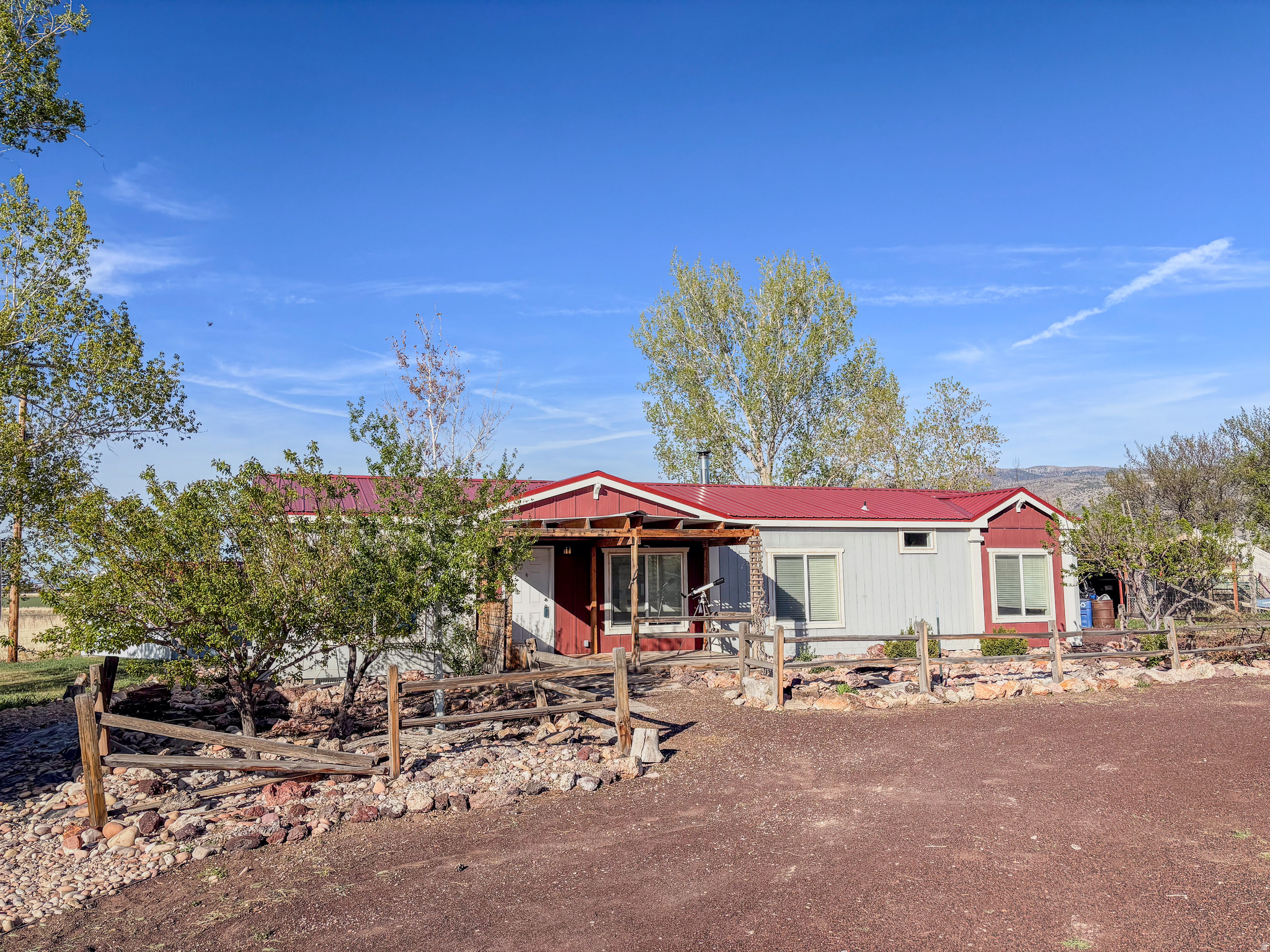 Experience the perfect blend of country living and outdoor adventure with this 3 bedroom, 2 bath home set on nearly 5 acres and packed with features. Inside, you'll find spacious living areas, a cozy wood-burning stove, and a large kitchen with modern appliances. The primary suite includes a dual-sink vanity, walk-in shower, and a walk-in closet. The fully fenced property includes a mature orchard producing a variety of fruit-primarily apples, along with pear, plum, apricot, peach, and cherry trees. Additional improvements include a detached two-car garage, shop, shed, and chicken coop. There are 3 RV hookups in place. The property is sold with 2.5 acre/ft of irrigation shares. Outdoor enthusiasts will appreciate the proximity to Corn Creek Canyon, Meadow Hot Springs, and nearby lava tubes, along with access to an extensive ATV trail network-offering year-round recreation right at your fingertips. Home is fixed to the land with a full stem wall foundation. Culinary water is provided by a well. Square footage figures are provided as a courtesy estimate only.  Buyer is advised to obtain an independent measurement.