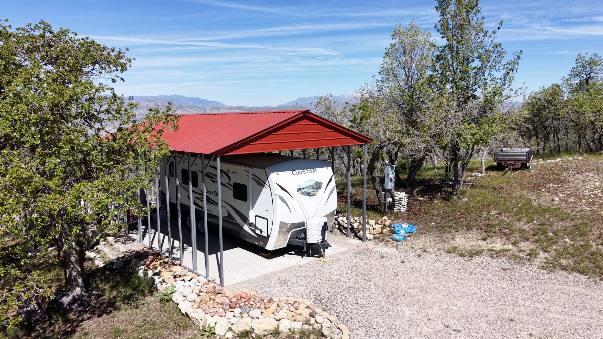 Escape to the mountains and start enjoying cabin-country living immediately with this beautifully improved recreational property in Skyline Mountain Resort. Perched to capture sweeping, unobstructed views of the Sanpete Valley, surrounding mountains, and spectacular sunsets, this turnkey setup is ready for weekends, summers, or year-round recreation.  The property includes a well-maintained 2015 Outdoors RV Creek Side 23RKS travel trailer, protected beneath a large metal RV cover and connected to existing utilities. Water is connected, hookups are in place for the trailer, and a water storage tank is included, providing convenience and peace of mind while enjoying your mountain getaway. Water is hauled from filling stations throughout the community.  Thoughtfully improved for outdoor living, the property features a spacious paver patio area, picnic benches for gathering with family and friends, and a powered storage shed-perfect for storing tools, toys, and mountain gear. Mature trees provide privacy and shade while preserving the incredible views that make this property so special.  Whether you're relaxing around camp, exploring the endless ATV and UTV trails accessible directly from the resort, golfing, swimming, or simply enjoying the quiet mountain atmosphere, this property offers everything you need for a true escape.