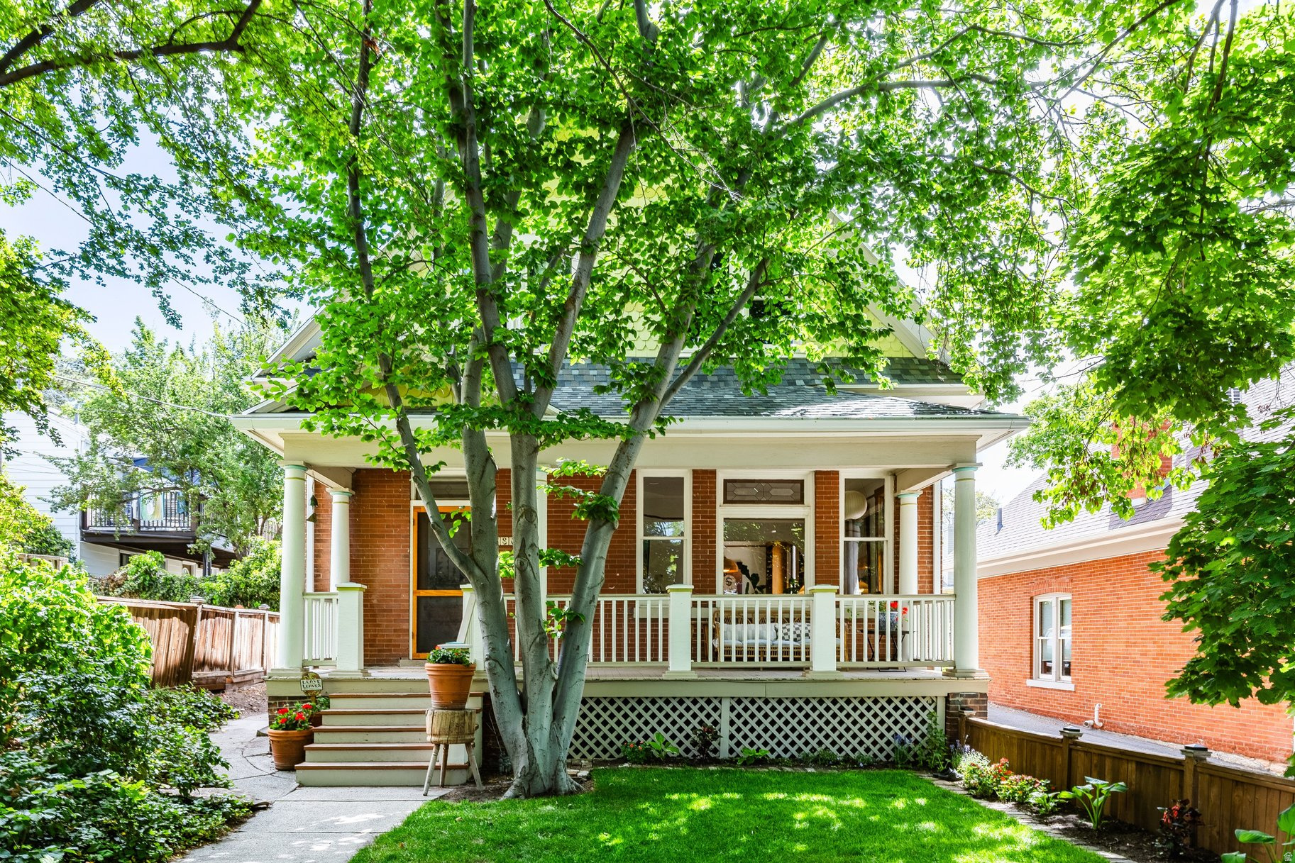 Experience rare privacy and historic charm in this beautifully preserved Avenues home. Surrounded by lush greenery, the property features a deeply shaded front yard-averaging 10 degrees cooler than the street-and a charming backyard complete with a brick patio, ivy, and mature rose bushes. Inside, the home radiates historic character with its original molding, Italian tile, recently refinished hardwood floors, and subtle stained glass paired with functioning transom windows. On the main level, a formal entry leads to a custom-designed vintage kitchen featuring a spacious walk-in pantry. The living room boasts a working, wood-burning fireplace, while the dining room features a long tiled bench and custom display cases with shelving perfectly sized for a record collection. Updated heating and AC ensure modern comfort throughout. The upper level is ideal for families and professionals alike, keeping all three bedrooms upstairs. This includes an expansive primary suite that easily accommodates a king-size bed. Downstairs, a large, unfinished basement with a separate entrance includes a newly refinished bathroom and a utility sink. The space is currently used as-and perfectly suited for-an art studio and workshop. For outdoor living, you can enjoy summer evenings on the large, screened-in porch, which is ideal for intimate outdoor dining or simply cozying up with some tea and a book. Located just steps from the local library, Memory Grove, grocery stores, and shoreline trails, this quiet, friendly neighborhood offers the perfect balance for book lovers, outdoor enthusiasts, and anyone who appreciates original finishes and historic character.