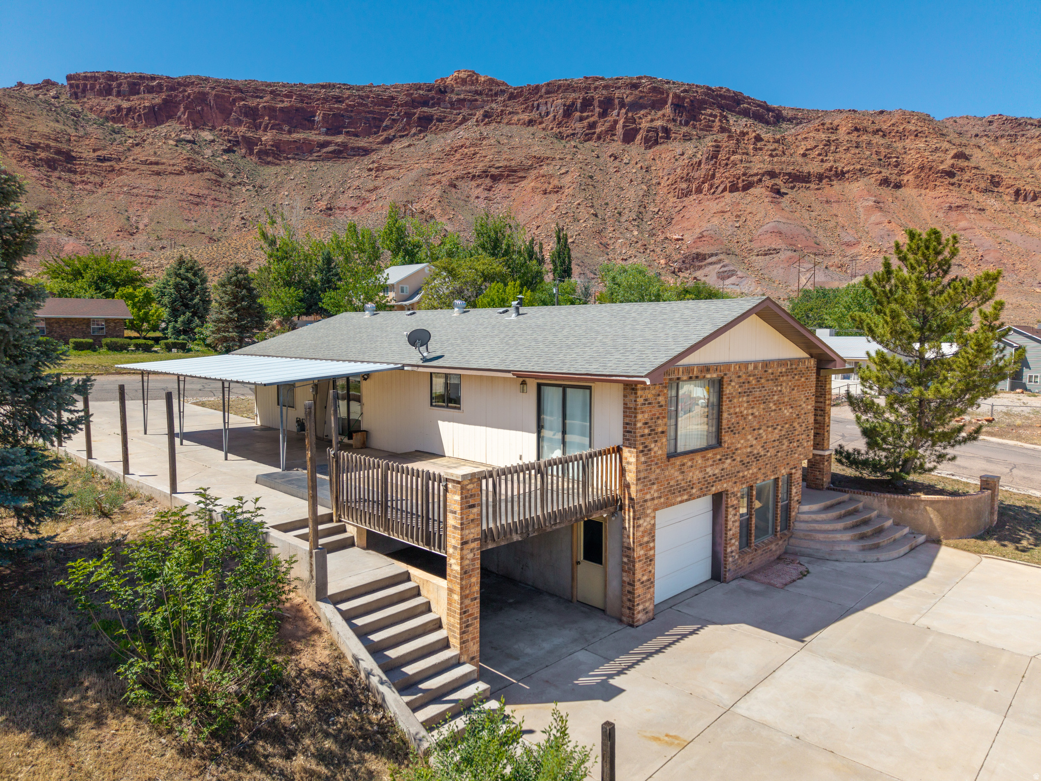 This custom 3-bedroom, 3-bathroom home was built in 1992 by an excellent, well-known local builder and features custom Al Heaton cabinets throughout with lots of parking and room to grow. The property is situated on a quarter-acre lot just off the highway in a less traveled neighborhood in Moab and offers main level living complete with a kitchen, livingroom, and 3 bedrooms including the master suite. The partial daylight basement features an office area, a family room, utility/laundry room, 1 full bath and abundance of storage. This home also has a lot parking options, including covered parking on the south side for main-level access with carport, plus an attached built-in tandem 2 car garage on the north lower side of the lot with an extra large concrete driveway with direct entry to the basement. The daylight basement provides significant flexibility with separate access. Recent updates include some high-priced maintenance items offering long-term peace of mind including a new roof (2024), a replaced main water line (2024), and a new refrigerator (2025). This is a solid, well built home ready for your personal touch with a great layout and space to adapt to your specific needs.  Square footage figures do not match county, buyer is advised to obtain an independent measurement.