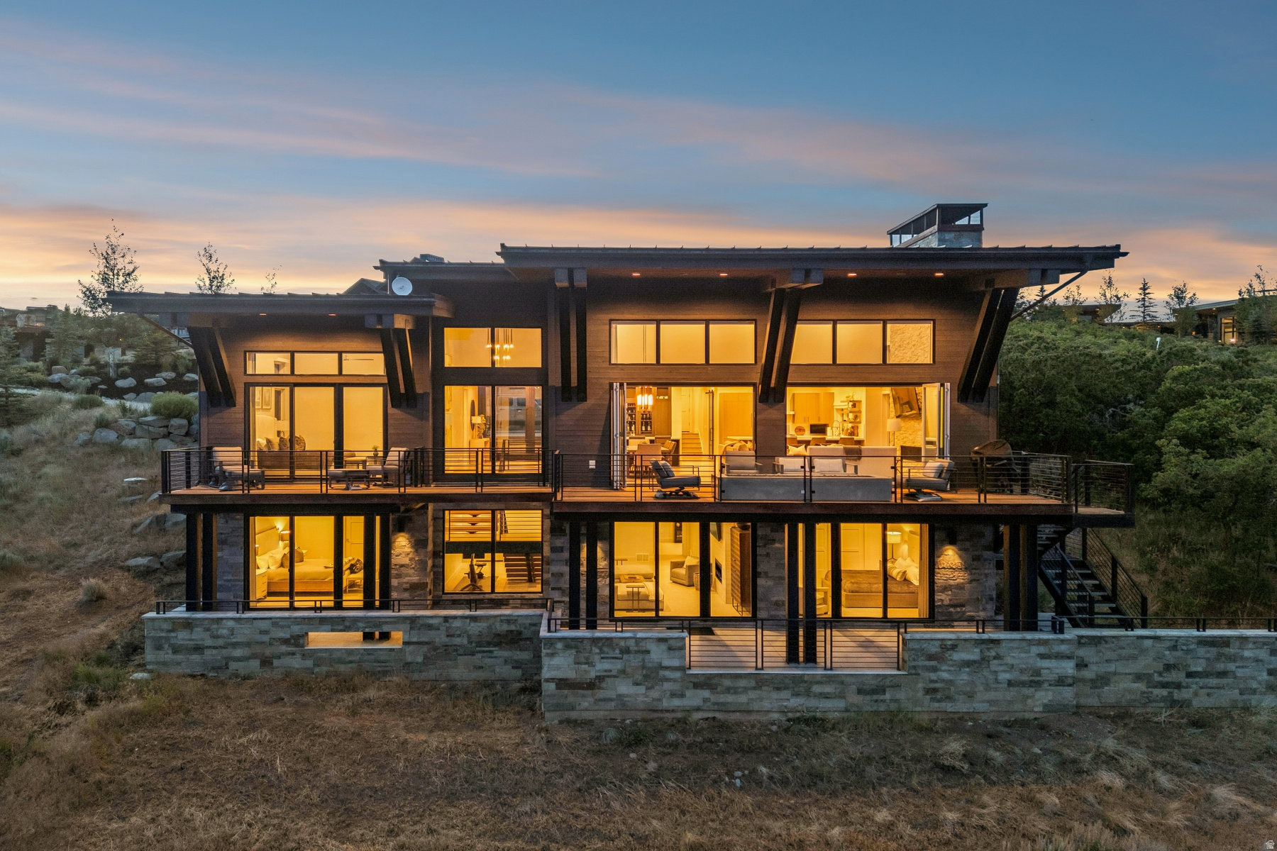 Modern Mountain Living with Panoramic Deer Valley & Uinta Views -- Located along quiet Sunrise Loop, one of Promontory's favorite streets for morning walks, dog walks, and enjoying the peaceful surroundings, this exceptional contemporary mountain home captures sweeping views of Deer Valley Resort, the Uinta Mountains, and the surrounding rolling hills. Situated on 1.22 acres along quiet Sunrise Loop, the home offers both privacy and convenient access to Promontory's award-winning amenities. Designed for effortless main-level living, the 5,279 square foot floor plan features four spacious ensuite bedrooms, five bathrooms, and a dedicated office, creating an ideal balance of luxury and functionality. Expansive walls of glass fill the great room with natural light while seamlessly connecting the living, dining, and kitchen spaces to generous outdoor decks designed for year-round entertaining. A striking floor-to-ceiling stone fireplace anchors the great room, while the adjacent main-level bar creates the perfect setting for hosting family and friends. The chef's kitchen is complemented by clean contemporary finishes, oversized island seating, and thoughtful design throughout. The main-level primary suite enjoys its own private deck, spa-inspired bath, and spectacular morning views. Additional features include a heated driveway, oversized garage, and quality construction completed in 2019. Whether enjoying sunsets around the outdoor fire pit, working remotely from the dedicated office, or entertaining guests indoors and out, this home offers the mountain lifestyle today's buyers are seeking. A Promontory Club membership is available through a separate transaction with Promontory Club, providing access to world-class amenities including championship golf, private ski lodges, fitness facilities, pools, spa, beach club, tennis and pickleball, dining venues, equestrian facilities, miles of trails, and more.