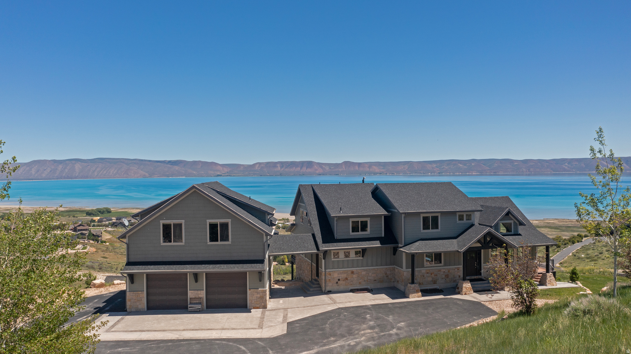 Named Falcons Landing for a reason, this extraordinary custom home with a separate ADU in The Reserve at Bear Lake showcases some of the most breathtaking panoramic views in the area. Designed to capture the beauty of Bear Lake and the surrounding mountains from nearly every room, the main home features six bedrooms, including a luxurious main-level primary suite with an attached bath. The spacious great room is highlighted by expansive view windows in every direction, custom inlaid wood and tile flooring, hand-cut real stone masonry, and exceptional craftsmanship throughout. State-of-the-art decking and railing systems create the perfect setting for enjoying the stunning scenery, while the fully landscaped grounds provide a beautiful outdoor retreat. The upper level offers two bedrooms, one bathroom, and a loft area, while the lower level includes two additional bedrooms, a bathroom, and a large family and game room. A massive detached three-car garage is complemented by a two-bedroom, one-bath ADU above with a full kitchen, providing excellent guest accommodations or rental potential. Offered fully furnished and turn-key, this property is ready to enjoy from day one.  Located in The Reserve at Bear Lake, owners enjoy access to premier amenities including a lodge-style clubhouse with a fitness room, two seasonal heated pools, a year-round hot tub, splash pad, covered poolside pavilion, playground, sports courts for basketball, tennis, and pickleball, and gated private beach access to Bear Lake. The property also offers direct access to Fish Haven Canyon, providing endless opportunities for ATV and UTV riding, snowmobiling, snowshoeing, hiking, and mountain biking. Garden City, with its shops, dining, and famous raspberry shakes, along with the Bear Lake State Park Marina for boat launching and rentals, is just 10 minutes away, while Beaver Mountain Ski Resort is only 25 minutes from the property. Short-term rentals are allowed, making Falcons Landing an exceptional opportunity for both personal enjoyment and investment.