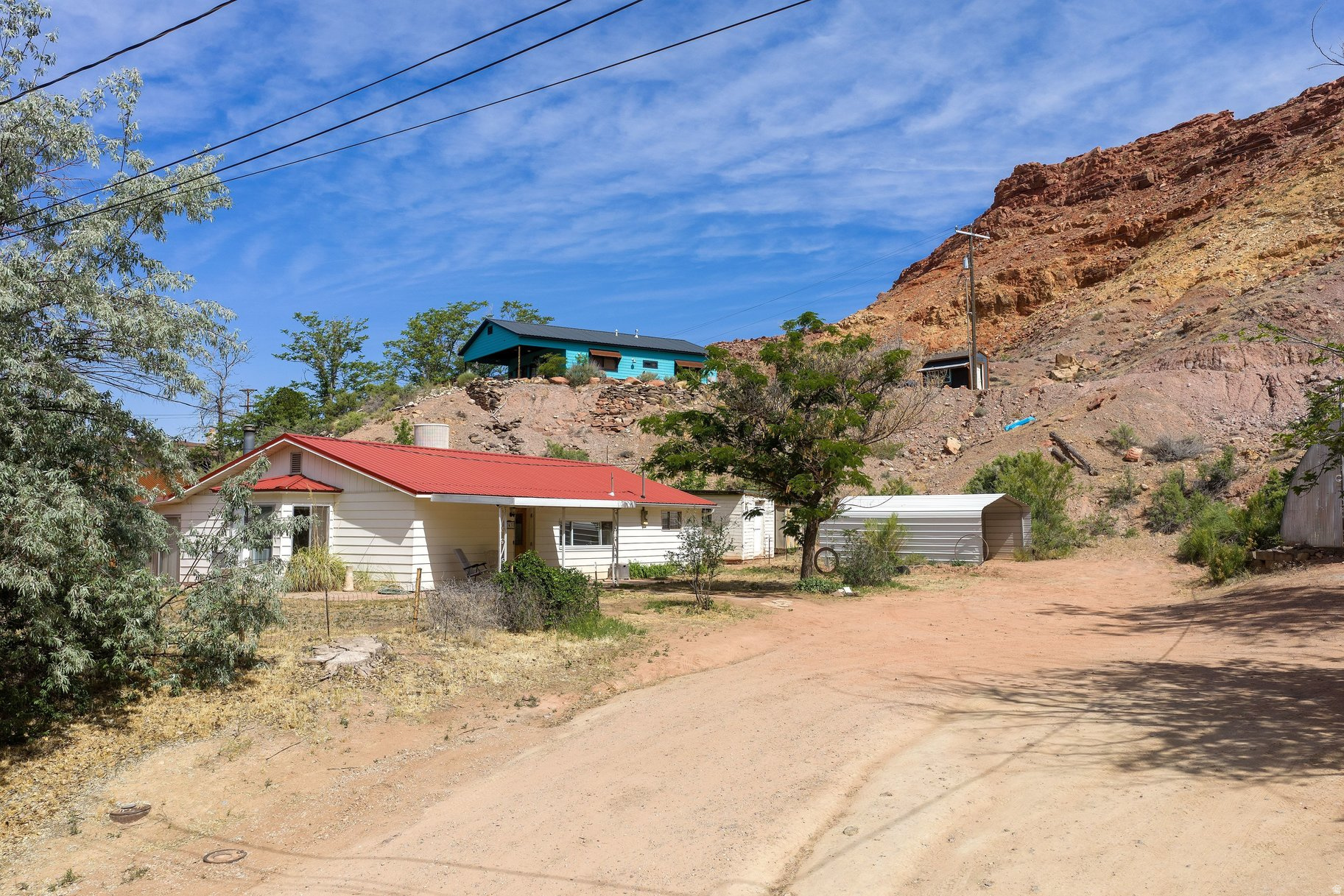 Fixer-Upper Opportunity  Priced to Sell!  Tucked away on a private road just a few blocks from the heart of Moab's Main Street, this unique 1.26-acre property offers space, potential, and a rare opportunity to create something truly your own. Surrounded by the natural beauty of the area, the setting provides both privacy and convenience, with easy access to shops, dining, and outdoor adventure.  The home features 2 bedrooms and 2 bathrooms, offering a flexible layout ready for your vision. This is a true fixer-upper, ideal for buyers looking to renovate, invest, or design a personalized retreat from the ground up. The expansive lot includes five outbuildings and sheds, providing ample room for storage, workshops, or creative use.  A charming gazebo with a hot tub adds a special touch to the property, creating a relaxing space to unwind and take in the peaceful surroundings. With over an acre of land, there is plenty of room for expansion, landscaping, or additional improvements to maximize the property's potential.  This property is being sold as-is, presenting a unique chance to invest in a desirable location with endless possibilities. Whether you're seeking a project home, an investment opportunity, or a future desert getaway, this Moab property is ready for its next chapter.
