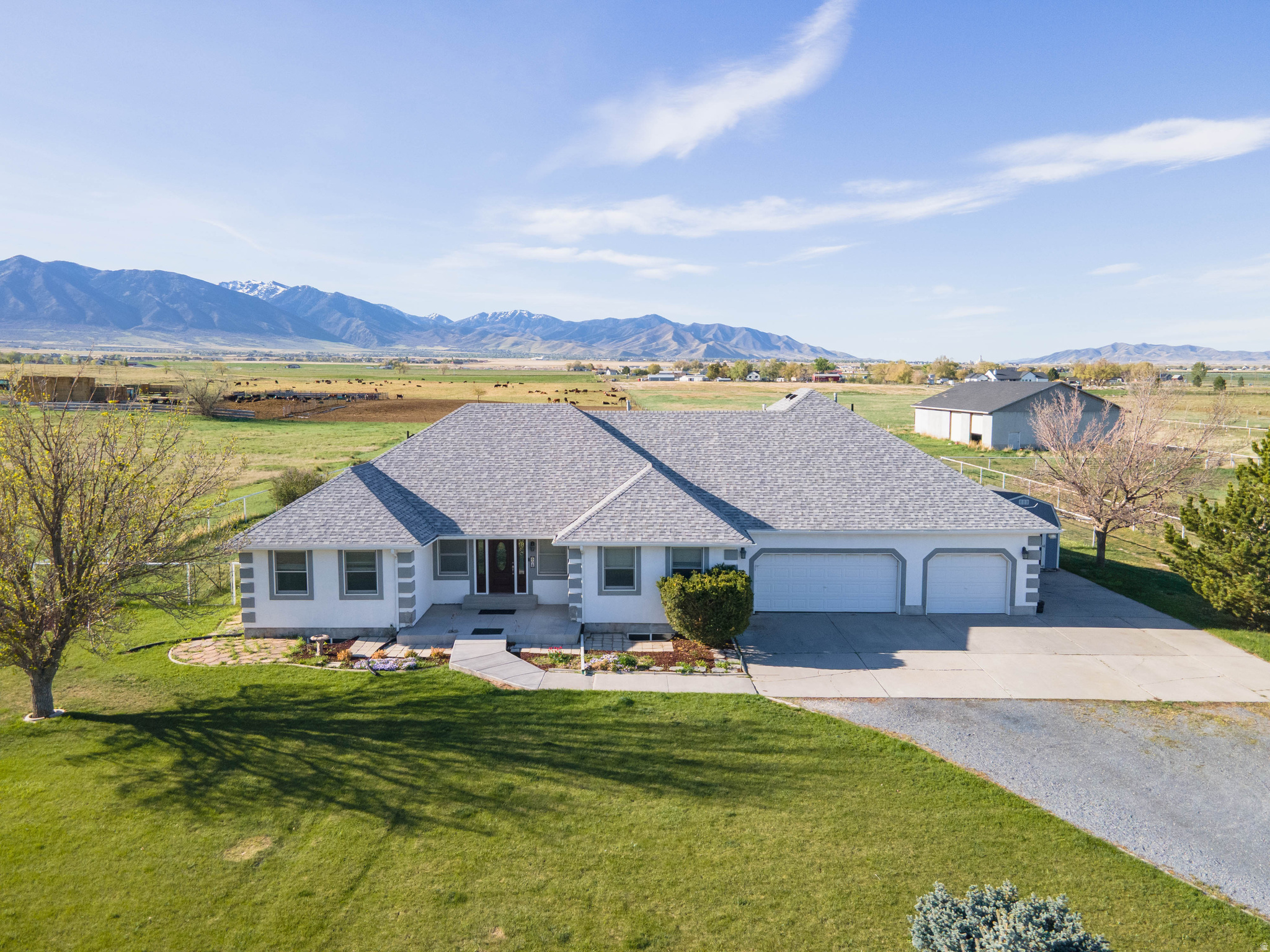 This property blends rural lifestyle with modern convenience-bring your animals, hobbies, and vision to make it your own.  The impressive 6,000+ sq ft home offers expansive living and entertaining areas, perfect for gatherings. The spacious primary suite is a true retreat, featuring a cozy fireplace and private walkout to the back patio-perfect for enjoying peaceful country views.  Downstairs, the fully finished basement includes a separate entrance basement apartment complete with kitchen, laundry, bath, bedroom and storage. An  additional kitchen area in the basement is already plumbed and ready for completion-ideal for multi-generational living.  The land is fully cross-fenced with durable drill pipe fencing, ideal for rotational grazing and livestock management. A 50' x 80' concrete walled shop with mezzanine provides ample space for equipment, projects, or storage.  Property has an 8 inch private well and 2 acre feet of water is included with additional water available to purchase via water right 15-3800 and 15-3848.   Square footage figures are provided as a courtesy estimate only and were obtained from private measurement.  Buyer is advised to obtain an independent measurement.