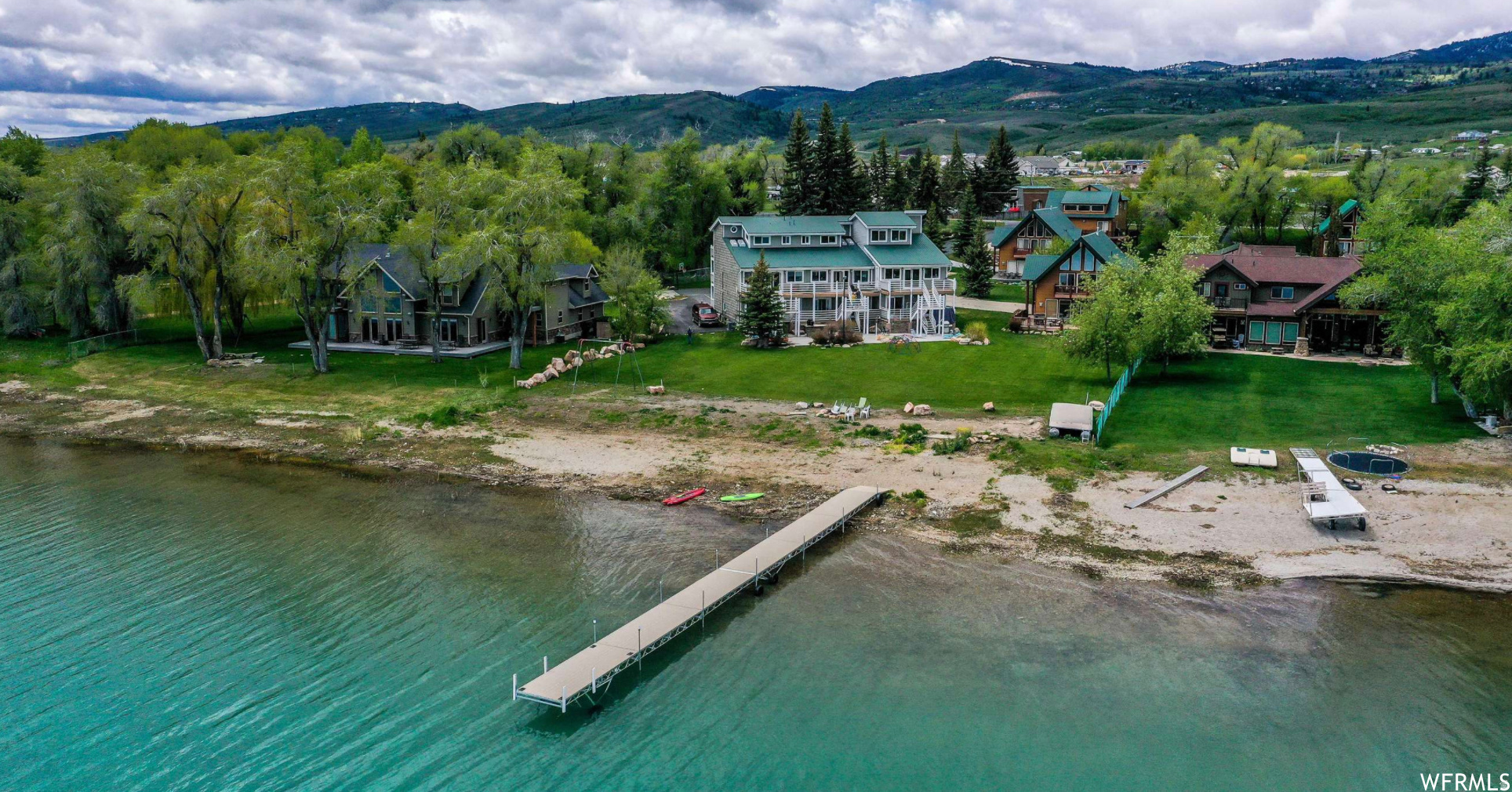 Rare opportunity to own an incredible beachfront townhome on the shores of beautiful Bear Lake, perfectly located within walking distance to restaurants, shake shops, stores, and Bear Lake State Park Marina. This spacious retreat features four bedrooms, three bathrooms, and comfortably sleeps up to 18 guests, making it ideal for gatherings, vacations, or investment use. The bright and open kitchen, dining, and living areas are designed to maximize the stunning lake views, while two levels of decks provide the perfect setting for relaxing, entertaining, and enjoying the breathtaking scenery. Spend warm summer evenings grilling outdoors, gathering around the firepit, or watching the kids play on the expansive 2/3-acre lawn complete with a playset. The property also includes access to a private beach and an 80-foot dock shared with only five other properties, offering exceptional lakefront enjoyment for boating, swimming, and paddleboarding. Nightly rentals are allowed, creating an outstanding opportunity for both personal enjoyment and rental income potential.