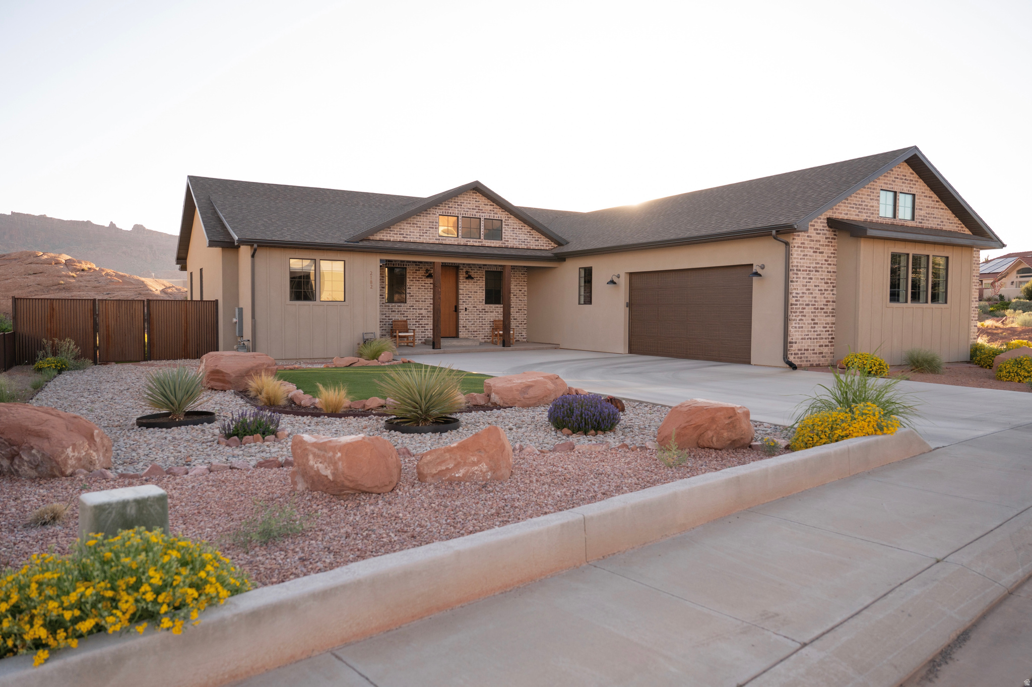 Stunning Custom Home in Coveted Puesta del Sol! Step into a world of thoughtful design and sophisticated comfort in this exceptional 5-bedroom, 3.5-bath home set on nearly 0.4 acres of low-maintenance xeriscaped grounds, offering your own private piece of iconic red rock. From the moment you enter the welcoming foyer, this home balances elegance and functionality with seamless flow and abundant natural light. Curved doorways, expansive windows, and carefully considered architectural details create a sense of refinement throughout. The heart of the home is a light-filled living room, perfect for both everyday living and entertaining. A glassed-in dining area with panoramic views complements the gourmet kitchen, complete with stainless steel appliances, an oversized breakfast bar seating five, plentiful cabinetry, and a large pantry. The gas fireplace adds warmth and ambiance, while the adjacent mudroom and dedicated laundry with ample storage ensure practicality meets style. The main floor primary suite is a private retreat, featuring a luxurious ensuite with dual vanities, a gorgeous tile shower, and a massive walk-in closet with built-in shelving and drawers. Step through the sliding glass doors to your patio, where red rock vistas become part of your everyday backdrop. On the opposite side of the home, two additional bedrooms and a shared full bath provide comfort and privacy for family or guests. The lower level expands your living and entertaining options with two more bedrooms, a full bath, and a sprawling recreation room that invites movie nights, game days, or large gatherings. A drive-through garage adds convenience, while the exterior spaces offer a simple, serene environment designed for ease of living. Every element of this home has been carefully considered, from architectural curves and natural light to functional spaces that enhance daily life. Whether entertaining, relaxing, or enjoying the landscape, this home delivers an unparalleled blend of elegance, comfort, and versatility in one of Moab's most sought-after neighborhoods.