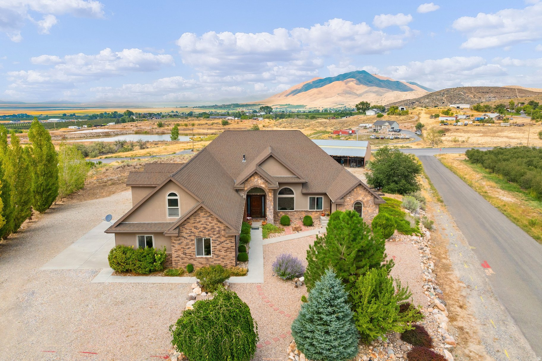 Welcome to this stunning custom Santa Festyle estate on 2.5 acres in Genola, offering breathtaking valley views and true country living with modern comfort. Designed with both functionality and charm, this property is ideal for horse enthusiasts and those seeking space to live, work, and play. The 48'x64' metal barn is fully equipped with water and power, making it a perfect fit for housing animals or recreational toys. Inside, soaring ceilings reach 14 feet in the entry and office, with 9-foot ceilings throughout the rest of the home. The open-concept floor plan flows seamlessly into a spacious kitchen featuring double-thick granite countertops, custom tile backsplash, an oversized island, and a remarkable 5'x17' walk-in pantry complete with counters and outlets for small appliances. Cozy reading and art rooms adjoin the main living space, anchored by a custom Santa Festyle fireplace with a pellet stove that can serve as an additional heat source. The extra-large primary suite offers custom granite and tile finishes as well as a generous walk-in closet. A private casita with its own entry, kitchenette, three-quarter bath, and laundry hookups provides a comfortable mother-in-law or guest suite. Upstairs, a nearly 700-square-foot bonus room with two large storage closets and its own half bath provides flexible space for work, play, or entertaining. The oversized 28'x40' garage is fully finished and features a deep sink, storage closet, and a mudroom with adjoining half bath. Beautiful flooring throughout the home includes hardwood, tile, marble, and carpet, all complementing the custom details. Expansive wraparound covered patios measuring 14'x74' creates the perfect space for entertaining while enjoying the mountain and valley views. If country living with modern convenience is what you love, this beautifully designed custom home is truly one of a kind. Square footage figures are provided as a courtesy estimate only and were obtained from an appraisal sketch. Buyer is advised to obtain an independent measurement.