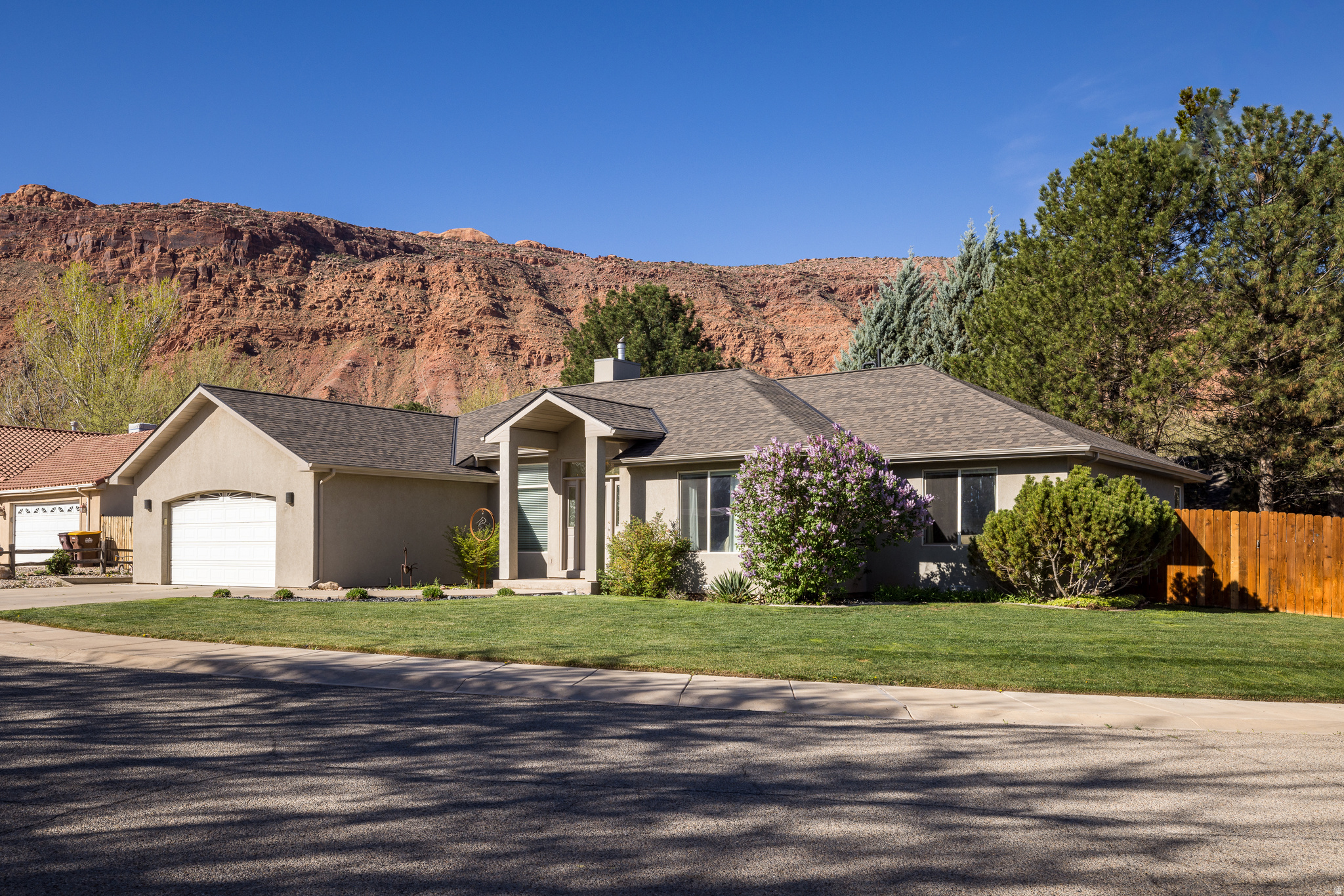 BACK YARD BEAUTY! This beautifully maintained Moab home is located on a charming cul-de-sac, offering a unique blend of comfort, space, and convenience. Just minutes from downtown, schools, parks, restaurants, and grocery stores, and only a few blocks from Moab's scenic pathways, this home places you right where you want to be. The home features 4 generously sized bedrooms and 3 full bathrooms, providing ample space for family, guests, or a home office. The primary suite offers a true retreat with a large walk-in closet and a well-appointed en-suite bath complete with a tile and glass block shower along with a jetted tub. The living room welcomes you with vaulted ceilings and a cozy gas fireplace, creating a bright and inviting atmosphere. The spacious kitchen is well appointed with a large granite island, offering plenty of room for cooking, gathering, and everyday living. Just off the kitchen, the dining area opens to the backyard patio and outdoor living space, creating an easy indoor-outdoor connection. Step outside to your back yard retreat designed for endless enjoyment, featuring lush green grass, a spacious patio, and a fire pit area, perfect for relaxing evenings or entertaining under the Moab sky. Don't forget the toys! The extra wide two car garage offers plenty of room for vehicles, storage, and all your adventure gear.  Square footage figures are provided as a courtesy estimate only and were obtained from images. Buyer is advised to obtain an independent measurement.