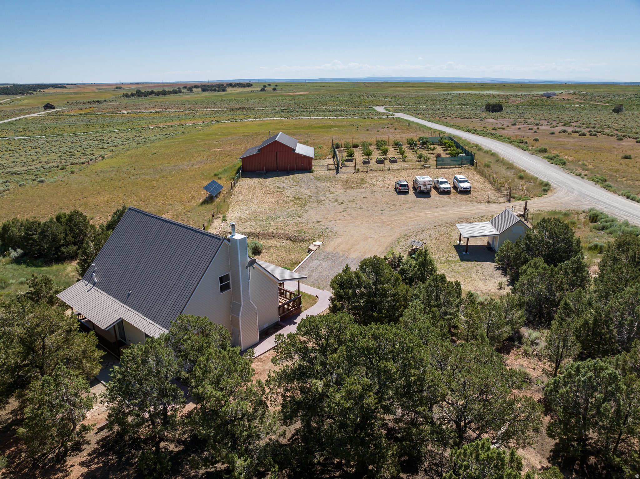 Escape to a beautiful, well cared for, six acre ranchette in Elk Meadows, just minutes north of Monticello. Breathtaking views of the La Sal and Blue Mountains await you with 1 residential acre blanketed in magical pine forest and 5 acres of fenced and gated agricultural land. The massive 40x42' barn with indoor/outdoor gated animal enclosure and tack room can cater to both large and small animals, vehicle/equipment storage, or even become your dream venture. A deer-proofed orchard and garden is a homesteader's dream with mature fruit trees and raised planting beds that are lush with water from your private well and coveted water rights. An additional, fully insulated building houses the power for the private well and the whole-house water softening system while also providing water to the full hookup RV pad. The modern farmhouse welcomes you into a cozy living room that opens out to a bright, spacious, up-to-date kitchen with charming box bay window seating and a large island, with plenty of room for all. The downstairs bedroom invites the forest right in through expansive windows and there is an added bonus room with closet and an oversized window overlooking the pines, perfect for an office, crafting, storage or an added sleeping area. A full downstairs bath adjoins a tiled mudroom and laundry room.  The upstairs living space is an incredibly spacious, open, primary suite with a full bath, an 8x10 walk-in closet and bonus sleeping loft, all flooded with breathtaking views of the majestic LaSal Mountains and Abajos. Significant updates include metal roofs, new siding, light and bright LVP flooring, a water heater, new paint, high-speed fiber internet stubbed to the lot, and a solar installation connecting six high quality 415 watt panels to a simple master switch that can be flipped to power the home completely off grid. A buyer can customize their power needs with their choice of batteries and inverters or simply live on the power grid. Once you've had enough wildlife watching and entertaining guests from your expansive front porch, you're only an hour to Canyonlands, Arches, and Bears Ears. You will not find another property like this!