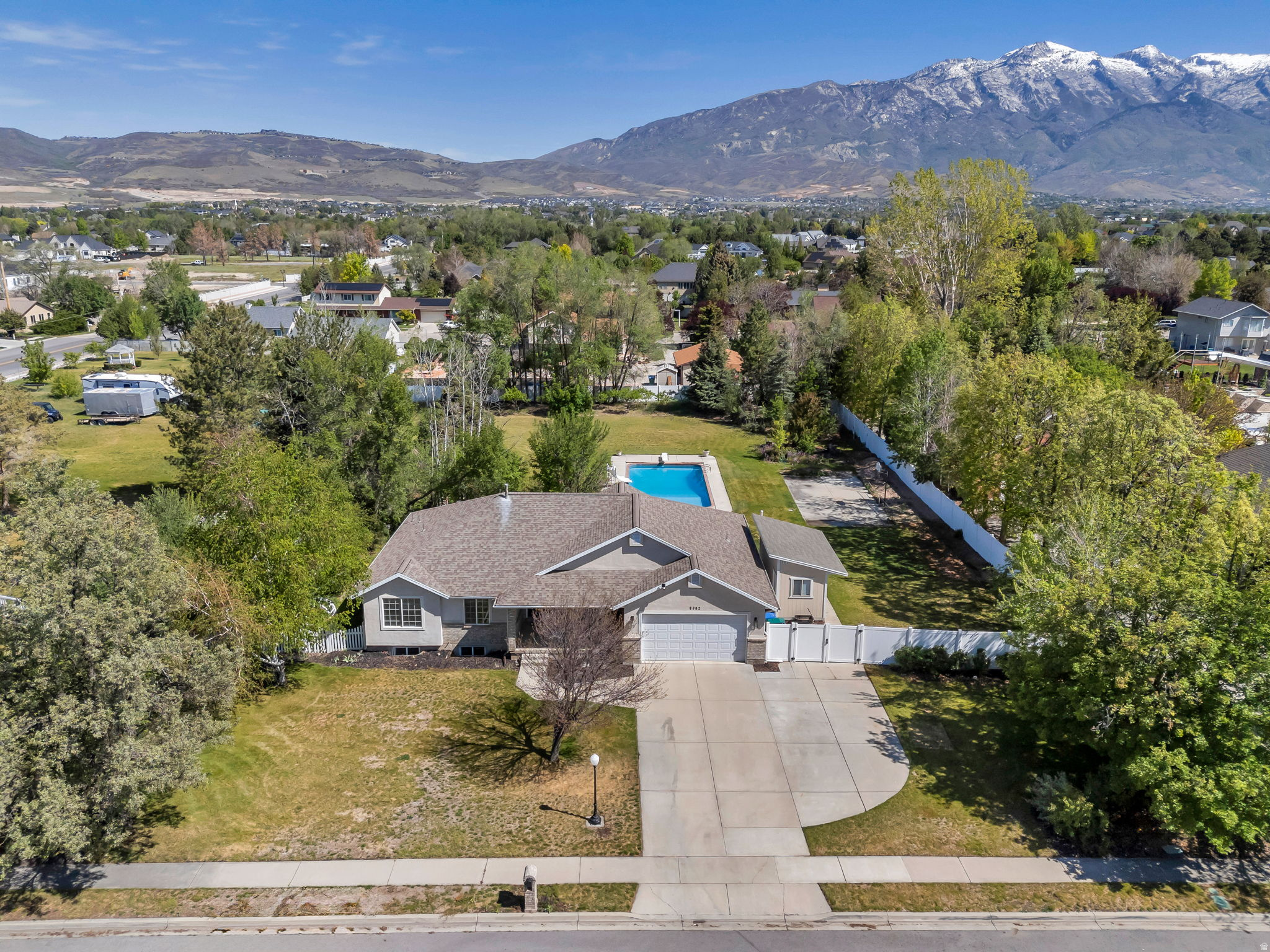 Stunning rambler on nearly an acre in Highland's peaceful Wren Haven neighborhood, with beautiful mountain views and a backyard built for unforgettable summers. The open concept main level features a fully updated kitchen with white cabinetry, quartz countertops, a gas range, double ovens, and an island with seating, flowing seamlessly into the spacious living area with a cozy fireplace and French doors leading to the back deck. A separate formal living room with glass-paned doors and a bay window offers the perfect flex space for a home office or additional sitting room. The primary suite includes an ensuite bathroom with dual sinks, a separate tub and shower, and a generous walk-in closet. The fully finished basement expands the living space with a large family room and ample storage. Outside, the fully fenced backyard delivers something rare at any price point: a large deck, paver patio, fire pit tucked among mature trees, a concrete sport court with basketball hoop, and an in-ground pool with a slide, diving board, and a cover. The 0.91-acre lot provides the space and privacy that is increasingly hard to find in Highland. Conveniently located near top-rated Alpine District schools, parks, shopping, and dining. Measurements provided as a courtesy only, buyer to verify all info.