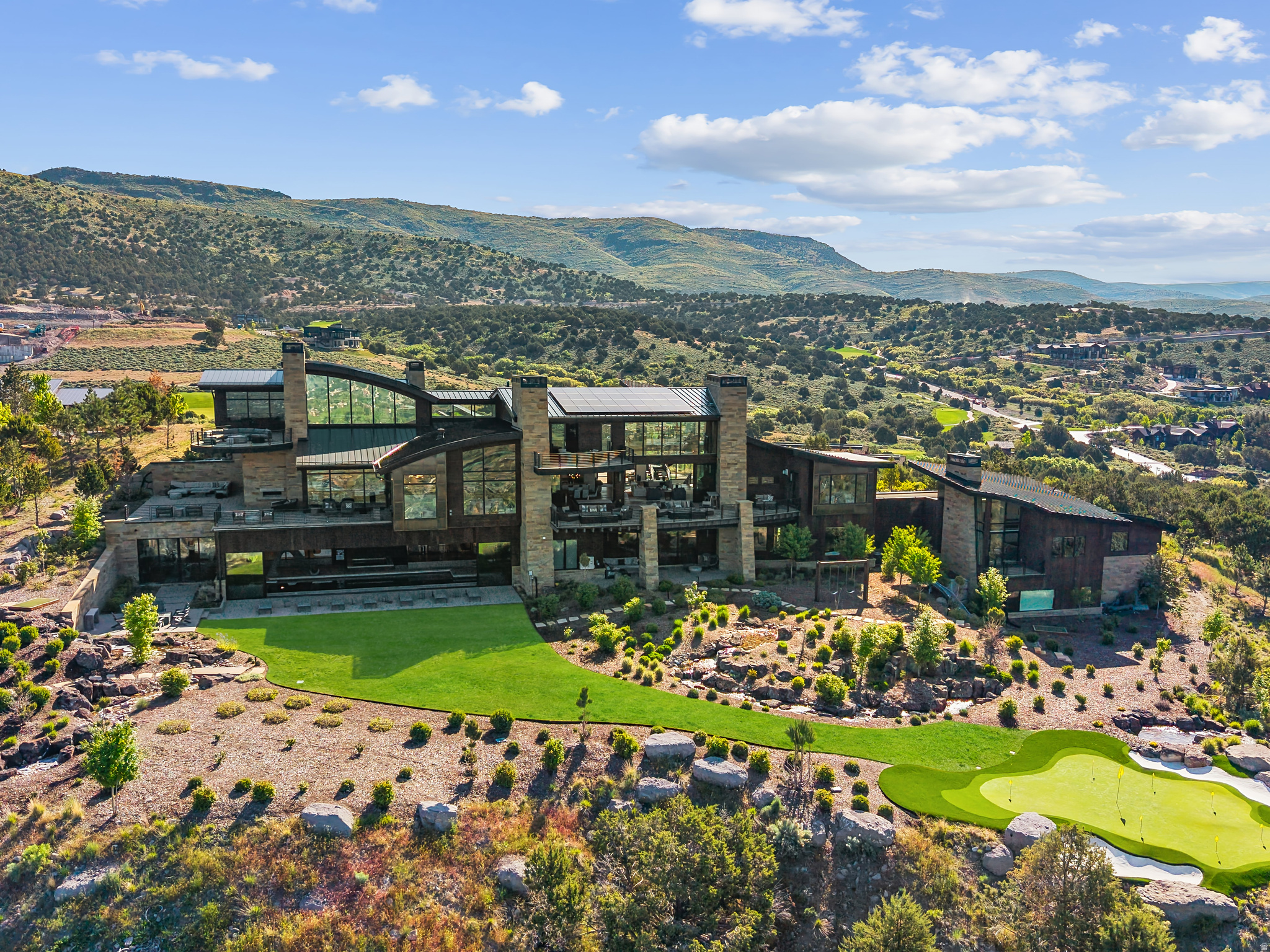 Elevated above the rest, this striking mountain estate claims one of the most commanding ridgelines within the coveted Red Ledges gated community, offering panoramic views that sweep across the Wasatch Range and Heber Valley. Designed by visionary architect Michael Upwall and brought to life by the renowned Shawn Johnstun, this exceptional residence blends bold architectural form with the warmth and function of a true legacy retreat.  Just 15 minutes from Deer Valley Resort, the home balances alpine seclusion with resort-level accessibility. Nearly 21,000 square feet of thoughtfully designed living space offers an extraordinary backdrop for both intimate moments and grand entertaining. Every detail has been considered, with timeless materials, flawless craftsmanship, and seamless indoor-outdoor flow throughout.  World-class amenities include an indoor sport court, a fitness suite with private sauna and steam rooms, a 50-foot indoor pool and spa, and a 2,000 square foot rooftop putting green with sweeping alpine vistas. A state-of-the-art indoor golf simulator ensures year-round play, no matter the weather. Expansive terraces with fire features and built-in audio create the perfect setting for relaxed mountain evenings and unforgettable events. The home offers 7 bedrooms and 11 bathrooms, including a serene primary wing, a two-bedroom private guest casita with full kitchen and garage, and a whimsical custom bunk room designed to host generations of guests in style. Offered fully furnished with custom-selected pieces and artwork, the interiors are ready for effortless move-in. The grounds are as extraordinary as the interiors, with cascading water features, massive Wyoming boulders, manicured lawns, and a private 75-yard par 3 golf hole with an infinity-edge green. It's all surrounded by the natural beauty and stillness of the mountain landscape. Red Ledges premier club amenities include the Jack Nicklaus Signature Golf Course, ski and adventure clubs.