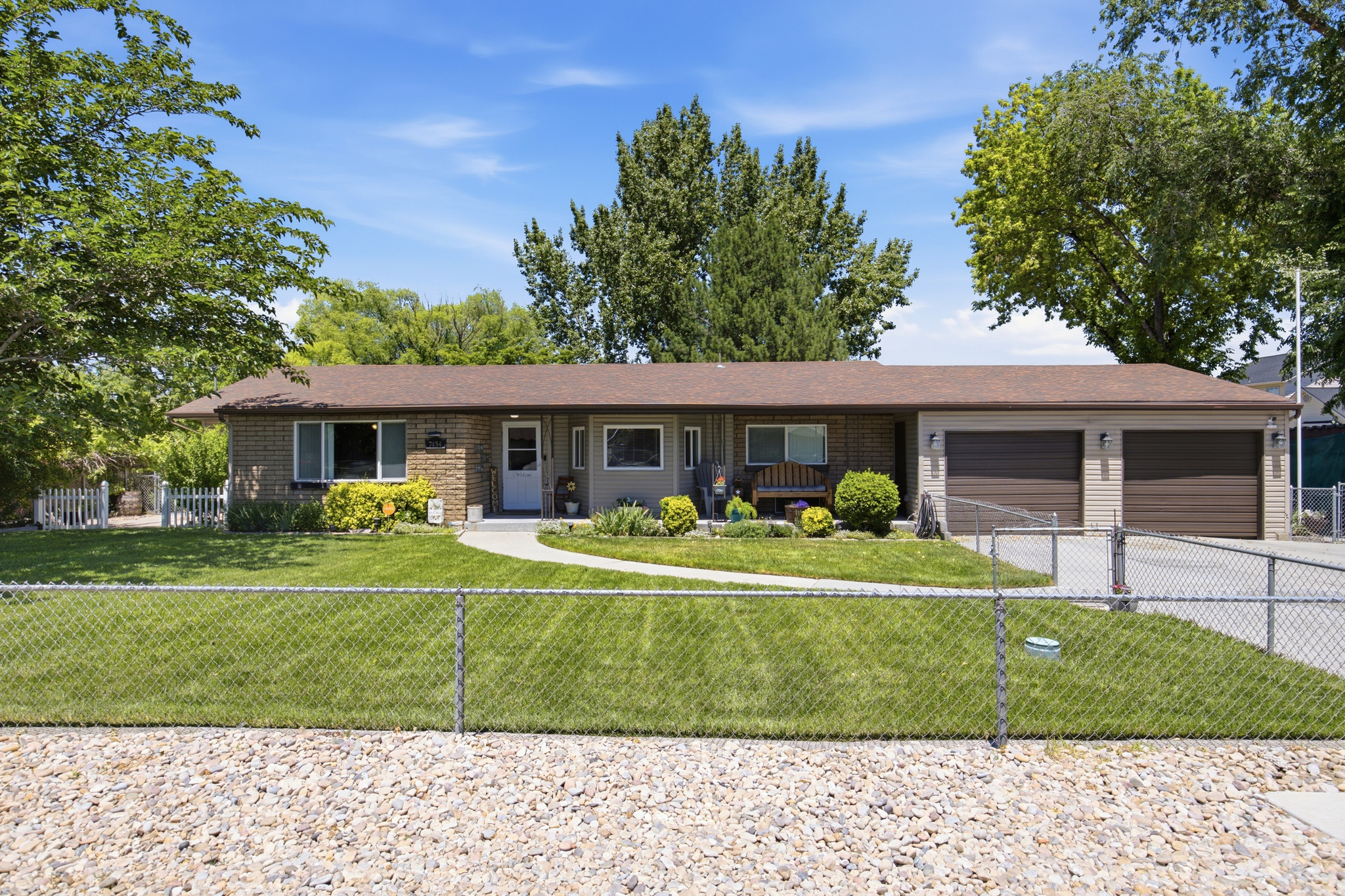 Welcome home to 7454 W 3100 S in Magna! This charming ranch-style brick home sits on a rare 0.55-acre lot tucked beneath a canopy of mature trees with breathtaking mountain views and delivers the kind of space, character, and lifestyle that is nearly impossible to find at this price point. With 4 bedrooms, 2 bathrooms, over 2,000 square feet of main floor living, and an outdoor space that truly has to be seen to be believed, this one checks every single box. The kitchen is the heart of the home featuring solid oak cabinetry floor to ceiling, stainless steel appliances, a center island with bar seating, generous counter space, a built-in desk area, and a bright dining nook wrapped in windows that flood the space with natural light. The living spaces are warm and inviting with gorgeous exposed wood beam accents, multiple ceiling fans, a wood burning stove, and a layout that gives everyone room to spread out and make it their own. The oversized primary suite is a true retreat with fresh LVP flooring, a bold navy accent wall, a sitting area with an electric fireplace, a walk-in closet, and an updated en suite bathroom with a custom wood framed mirror. Every additional bedroom is generously sized with fresh flooring and built-in shelving. The home also features a bonus lower level space perfect for a home office and food storage. Main floor laundry with built-in cabinetry and backyard access makes everyday living a breeze. Step outside and prepare to be impressed. The backyard is a private retreat featuring a massive covered patio with string lights, a dedicated fire pit area with seating, raised garden beds, a trampoline, a swing set, lush green grass, and towering mature trees that create a level of privacy you simply cannot replicate. The property also benefits from secondary water, keeping that half-acre yard green all season long. Worth noting, this property carries an A-1 Agricultural zoning designation, which is increasingly rare within Salt Lake County. This allows for animals, hobby farming, and a level of land use flexibility that most valley properties simply cannot offer. The extended 2-car garage with space for up to 6 vehicles, a massive concrete driveway, and dedicated RV parking round out everything on your wish list. Conveniently located with quick access to I-215, shopping, and everything the valley has to offer, all while feeling worlds away. Properties with this combination of location, land, and zoning do not come around often. Please allow 24 hours advance notice for all showings. 4 Beds | 2 Baths | 2,055 Sq Ft | 0.55 Acres | A-1 Agricultural Zoning | Secondary Water | Extended 2-Car Garage | RV Parking | Main Floor Laundry | Covered Patio | Fire Pit | Mountain Views | Magna, UT