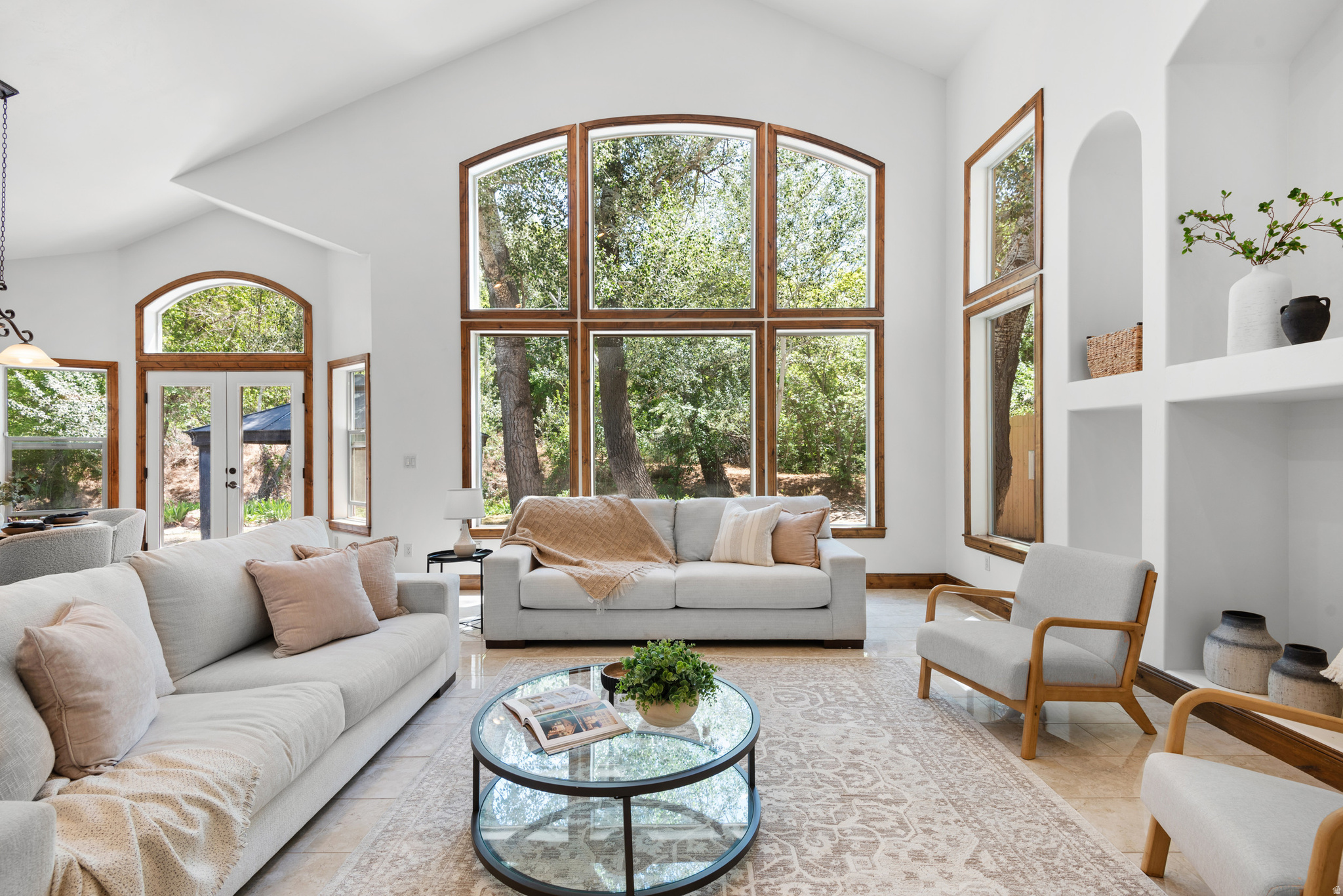 Tucked into a highly desirable Sandy neighborhood and framed by MATURE trees, this home seamlessly blends charm, comfort, and convenience. Just minutes from the Shops at South Town and the new Utah Mammoth facility, you can enjoy dining and shopping nearby while returning to a peaceful, picture-perfect retreat.  Step through a dramatic front entry that evokes the warm, rustic appeal of a SKI LODGE - exposed timber accents and rich finishes set the tone. Inside, a HIGH vaulted ceiling soars above a floor-to-ceiling stone fireplace and hand-scraped hardwood floors throughout. The chef's kitchen features granite counters, stainless appliances, double ovens, and a grand island that opens to sunlit dining and living spaces. Large windows flood the home with natural light and offer serene backyard views (and the occasional family of deer).  The primary suite is a true haven with a luxurious ensuite bath and one of the larger walk-in closets you'll find on the market. Enjoy outdoor living under the pavilion, ideal for relaxing or entertaining beneath the canopy of mature trees. A DEEP two-car garage with the depth to accommodate four cars, plus separate BASEMENT entrance accessible from the garage, complete this unforgettable property.