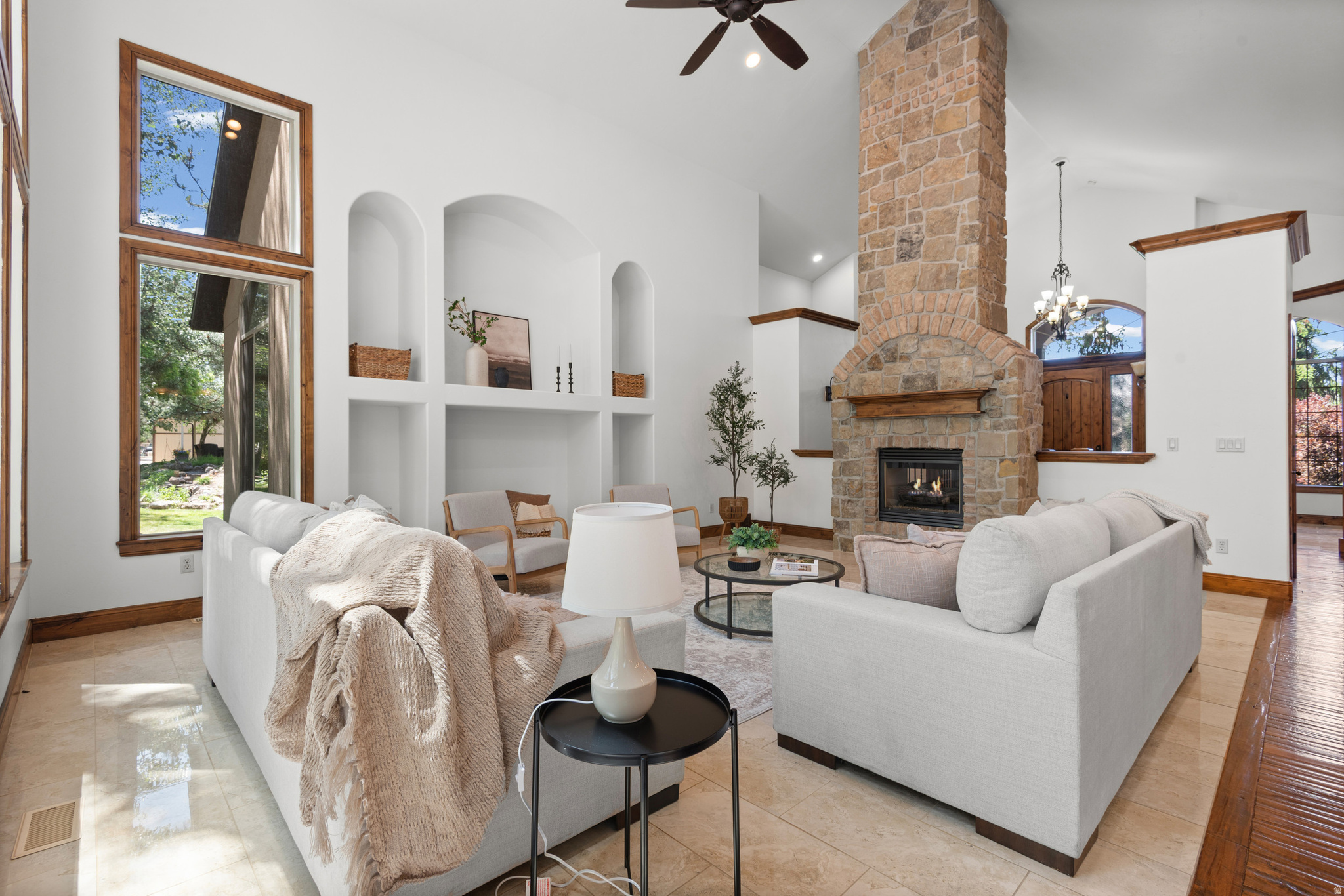 Tucked into a highly desirable Sandy neighborhood and framed by MATURE trees, this home seamlessly blends charm, comfort, and convenience. Just minutes from the Shops at South Town and the new Utah Mammoth facility, you can enjoy dining and shopping nearby while returning to a peaceful, picture-perfect retreat.  Step through a dramatic front entry that evokes the warm, rustic appeal of a SKI LODGE - exposed timber accents and rich finishes set the tone. Inside, a HIGH vaulted ceiling soars above a floor-to-ceiling stone fireplace and hand-scraped hardwood floors throughout. The chef's kitchen features granite counters, stainless appliances, double ovens, and a grand island that opens to sunlit dining and living spaces. Large windows flood the home with natural light and offer serene backyard views (and the occasional family of deer).  The primary suite is a true haven with a luxurious ensuite bath and one of the larger walk-in closets you'll find on the market. Enjoy outdoor living under the pavilion, ideal for relaxing or entertaining beneath the canopy of mature trees. A DEEP two-car garage with the depth to accommodate four cars, plus separate BASEMENT entrance accessible from the garage, complete this unforgettable property.