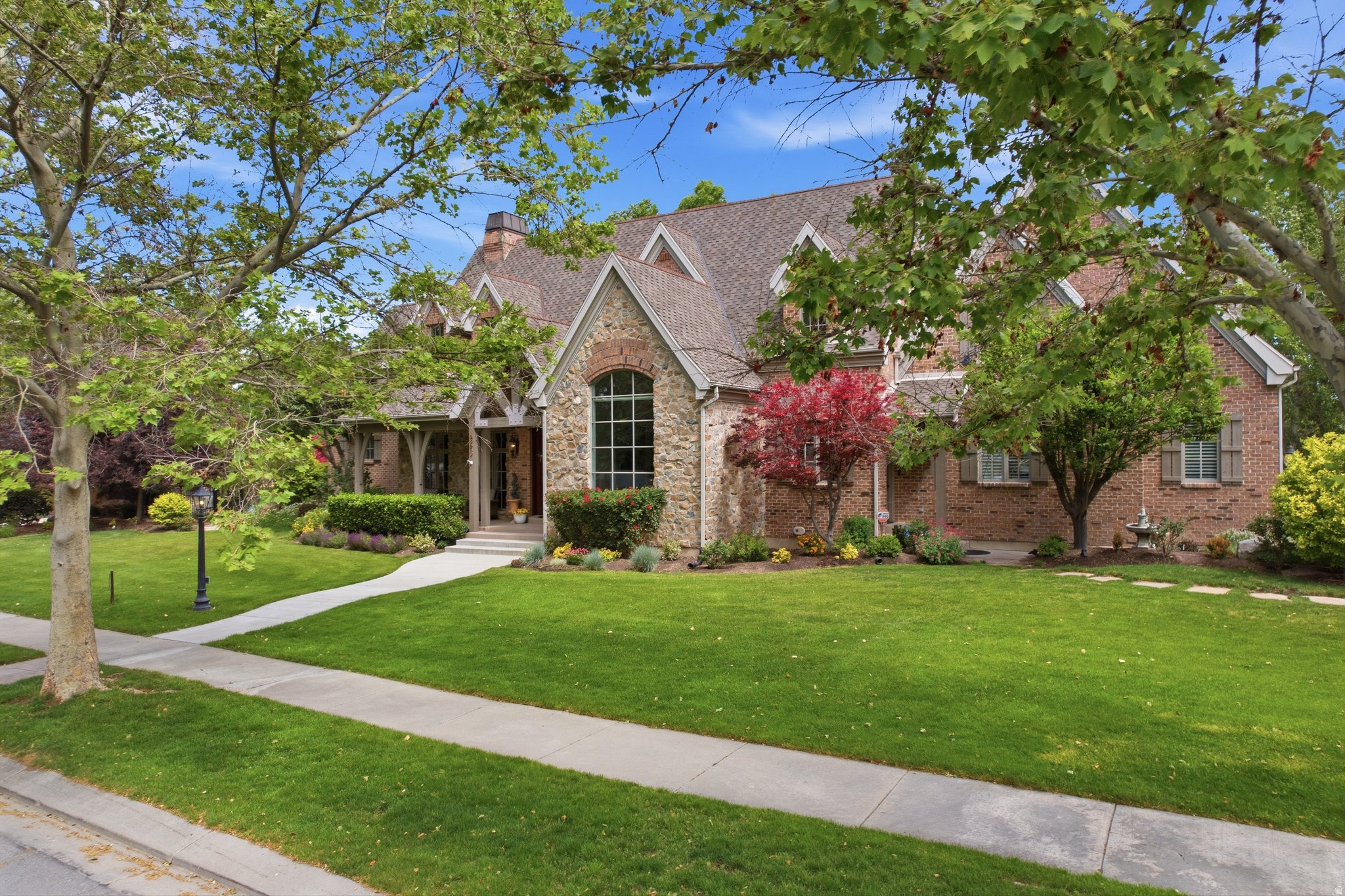 Nestled on one of Draper's most picturesque tree-lined canopy streets, this extraordinary estate sits on a private 0.61-acre lot and offers a rare combination of timeless craftsmanship, exceptional amenities, and breathtaking surroundings. The hand-crafted brick and real stone exterior, solid Brazilian cherry hardwood floors, Marvin wood-clad windows, and carefully curated architectural details create a home of enduring quality and character. Designed for both grand entertaining and comfortable everyday living, the open-concept floor plan features a dramatic two-story great room with a soaring 30-foot real stone fireplace and wood-beamed ceiling. The gourmet kitchen is equipped with granite countertops, a new Thermador range, hood, and oven, informal dining space, and a walk-through butler's pantry leading to the formal dining room. Offering exceptional flexibility, the home includes seven bedrooms, four en-suite bathrooms, two main-floor powder baths, three family rooms, a dedicated multi-desk office with custom built-ins, a large craft and wrapping room, and three storage rooms. The main-level primary suite serves as a private retreat with a luxurious en-suite bath, oversized walk-in closet with custom built-ins, and a center island featuring locking jewelry drawers. French doors open directly to a peaceful backyard sanctuary. The walkout lower level is designed for entertaining with a spacious theater room adjoining a full kitchen and gathering area. Additional features include three fireplaces, three air-conditioning units, four furnaces for consistent comfort throughout the home, solid wood four-inch shutters, an ADT security system, nine-foot basement ceilings, and laundry rooms on both the main and lower levels. Six French doors create seamless indoor-outdoor living and open to a truly remarkable backyard retreat. Enjoy an 11-foot-deep saltwater pool, a tranquil babbling stream, shaded dining beneath a pergola, and stunning views of a neighboring five-acre ranch filled with horses and wildlife. The heated four-car garage includes two EV charging outlets, and two water shares provide valuable secondary irrigation water. This is a rare opportunity to own a meticulously crafted estate offering privacy, elegance, comfort, and natural beauty in one of Draper's most coveted neighborhoods.    Square footage figures are provided as a courtesy estimate only and were obtained from previous listing MLS #2087276.  Buyer is advised to obtain an independent measurement.