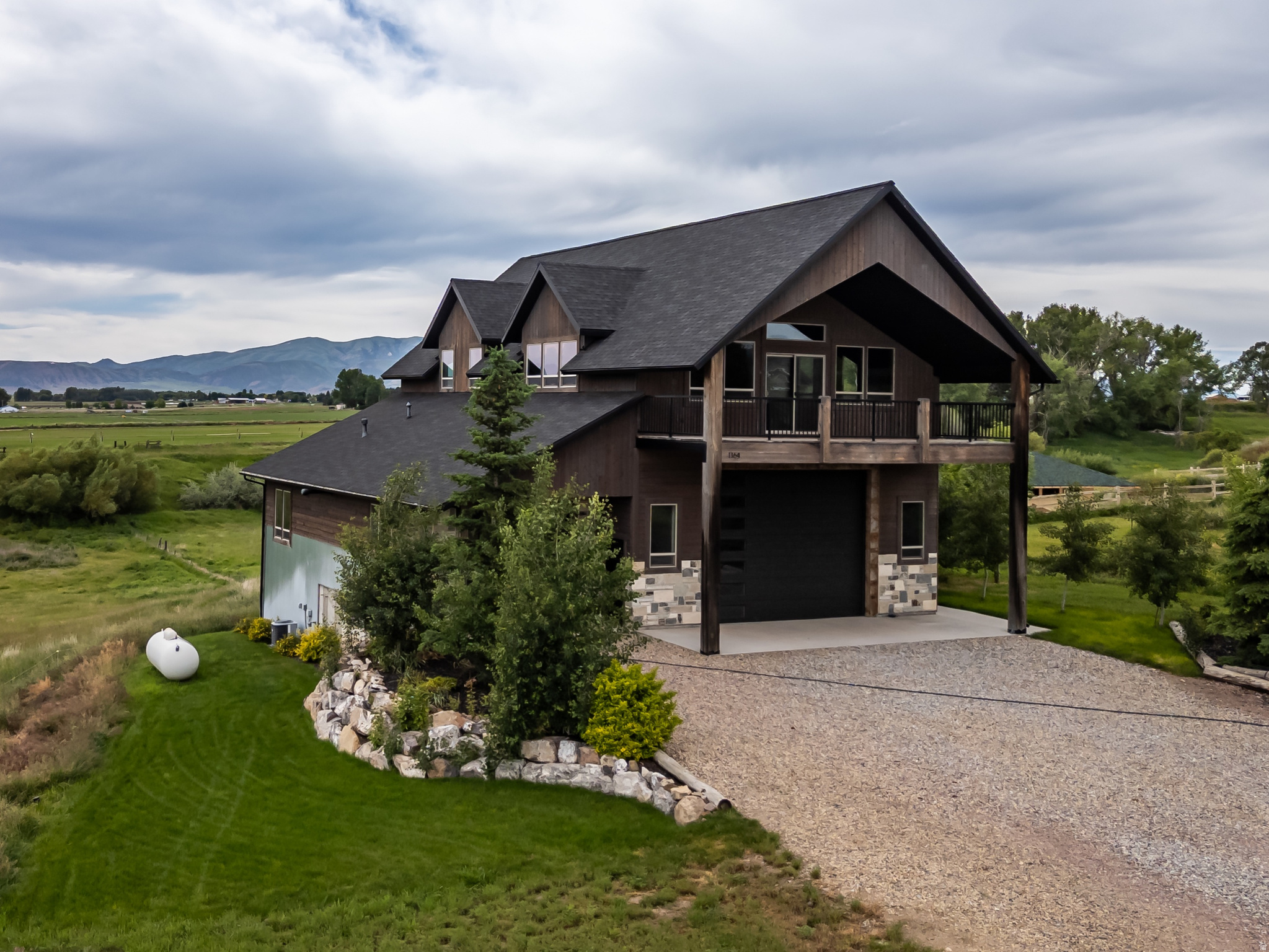 Perched atop a gently rolling hill and surrounded by sweeping mountain views in every direction, this custom-built home is a rare find. Nearly every window frames a postcard-worthy vista, while the 5.5-acre property offers serenity, space, and sustainability. A year-round stream flows peacefully alongside a scenic pond-perfect for enjoying quiet evenings and watching sunsets over the western range. Water rights for irrigation and a natural spring provide a sustainable, culinary-grade freshwater supply. Designed with both comfort and utility in mind, the lower level features an oversized 5-car garage-ideal for RVs, recreational toys, and workshop space. It's equipped with wiring for a mechanical lift and a 12+ foot high door for your largest vehicles. Upstairs, an expansive covered balcony invites you to start your mornings with sunrise coffee or unwind with evening grilling. Inside, rustic charm meets thoughtful design, with vaulted ceilings, a stunning stone fireplace, and walls clad in locally sourced, reclaimed barn wood. The spacious primary suite includes dual vanities, a walk-in shower, and a generous walk-in closet. The lower level also offers a full bath and a flexible office space-ideal for a guest suite, gym, hobby room, or lounge. A separate storage room with built-in shelving and a roll-up door provides ample space for outdoor gear and lawn equipment. Just 3 miles from the heart of picturesque Preston, Idaho and 23 miles to Logan, Utah, you'll enjoy the peace of country living with the convenience of nearby amenities. Several furnishings and key features convey, including a propane tank, water softener, sofa, kitchen table and chairs, barstools, and washer/dryer-making this move-in ready. This is more than a home-it's a lifestyle. Call the listing agent today to schedule your private tour of this one-of-a-kind sanctuary.