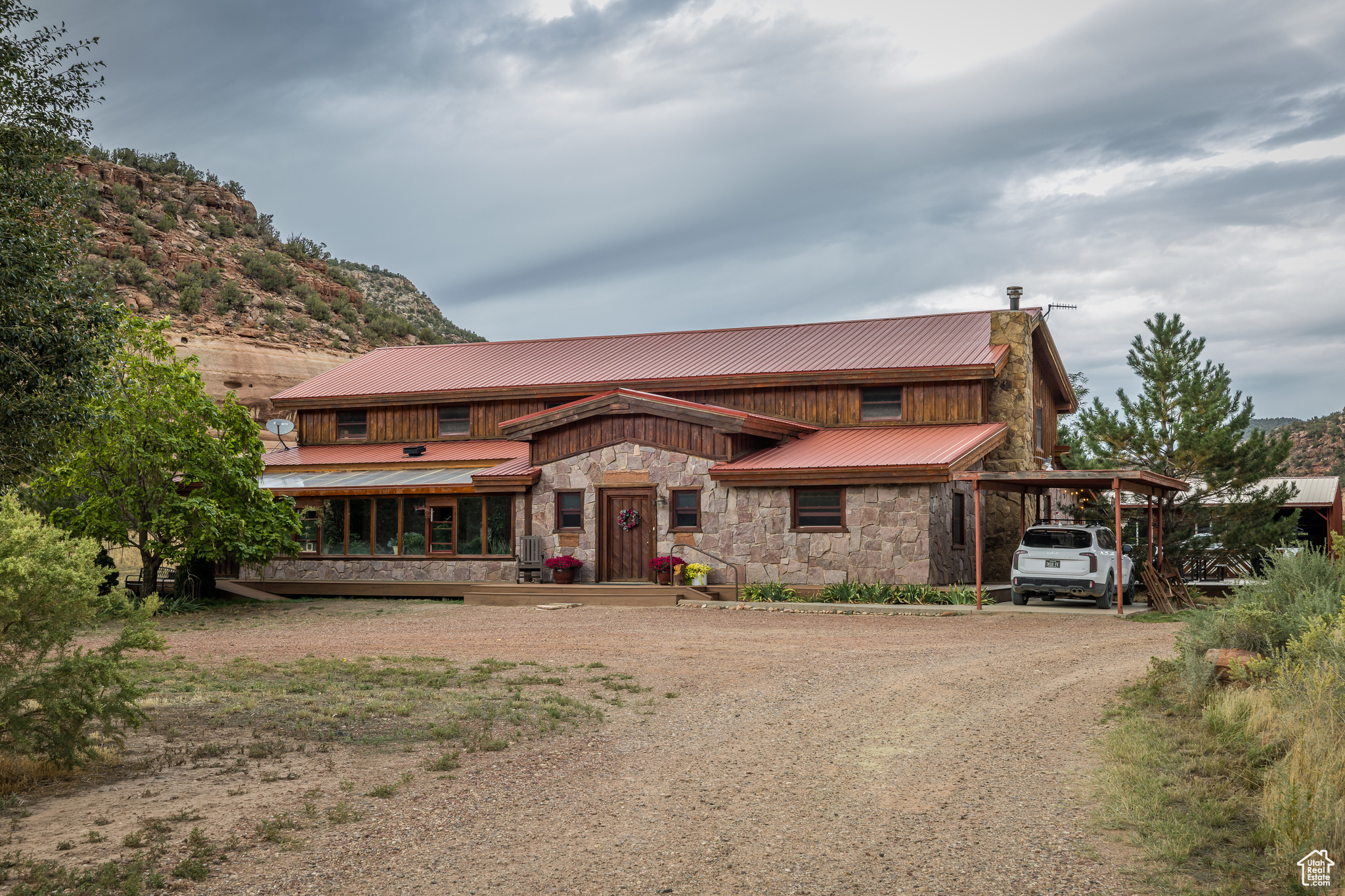 In the Valley of the Ancients, this incredible ranch property with two complete homes, offers a peaceful remote setting in picturesque Montezuma Canyon with red rock cliffs on both sides and an abundance of sites featuring artwork and ruins of Ancient Puebloans.  The canyon has been inhabited for thousands of years, in large part due to its favorable micro-climate and suitability for agriculture in the valley floor.  A premier property in the Canyon, Inclusive of 1,000 feet of Montezuma Creek, offering a furnished 7,300 square foot, 7-bedroom, 4-bathroom main home on three levels with a variety of entertaining, gathering and sleeping options.  Featuring a formal living room, extraordinary great room with formal dining room, open kitchen, generous family room and cozy conversation area centrally focused on the rock wood-burning fireplace with built-in pizza oven. The main level also includes 3 separate bedrooms, a 2-bedroom en-suite with a separate sitting room, two additional bathrooms, plus an indoor greenhouse atrium and access to the open patio.  The upper level has a gorgeous wrap around loft overlooking the main level, housing a game room with pool table and sleeper sofas, two separate sitting, sleeping or dining areas and access to a primary bedroom en-suite with loft, den, walk-in closet, gorgeous walk-in shower, and private balcony. The lower level of the home has a family room, plentiful storage and a bunk room that sleeps 14! In addition to all the main home has to offer, there is a 1,000 square foot guest house with 2 bedrooms, 1 full bathroom, loft, balcony and charming porch.  Crafted for off-grid comfort and sustainability on 36 acres with a private well, two septic systems, Outback lithium solar system, backup generator, 25'x50' hoop greenhouse, chicken coop, and multiple outbuildings.  The fenced orchard offers 140 fruit trees that bring glorious blossoms in the spring, and produce commercial quantities of apples, pears, peaches, cherries, apricots, and 7 varieties of plum, along with asparagus. Ready for your equestrian and large animal needs with irrigation-ready pastureland, two corralled horse stalls and multiple fenced-in areas. Accessible via a well-maintained County Road, the property sits about ten miles from the main thoroughfare, south of Monticello, home of the 24th nationally ranked Hideout Golf Course. Centrally located from Arches, Canyonlands and Mesa Verde National Parks, Lake Powell, Indian Creek, Moab, Utah and Cortez, Colorado.  This beautiful ranch would make an extraordinary get-away retreat, with perfect housing for your on-site manager, a vacation lodge or embrace the magnificent canyon as your year-round residence and enjoy a lifestyle that cannot be matched in the Four Corners region!