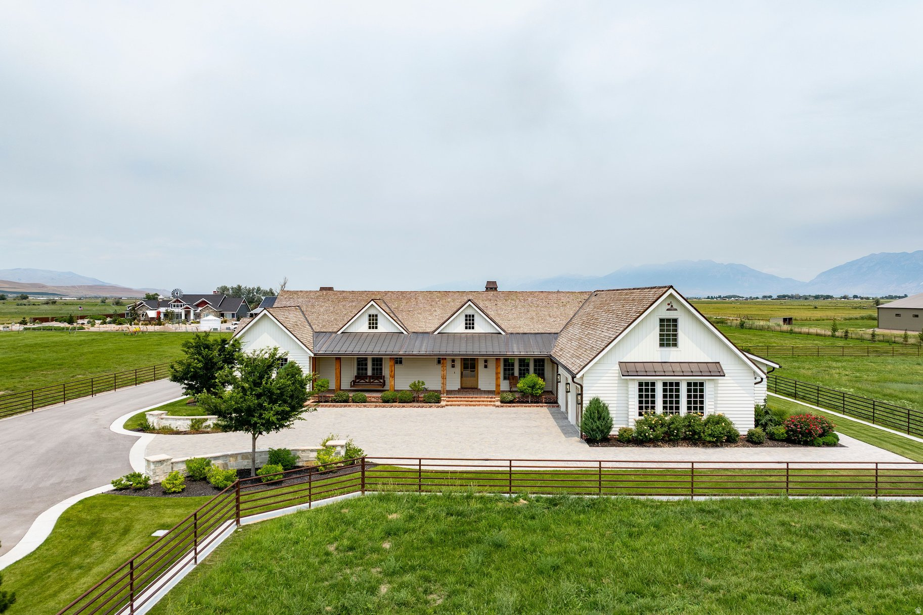Set on approximately 41 acres in the open countryside of southern Utah Valley, this exceptional equestrian ranch combines professional horse facilities with a stunning 5,415 square foot farmhouse that looks as though it was lifted from the pages of a magazine. A substantial new cutting horse facility anchors the property, featuring an impressive indoor arena with radiant overhead heaters, heavy duty ventilation, 10 stalls, cattle holding pens, and space to finish out an expansive gathering area for friends and family. Additional facilities include a separate five stall barn with two large garages and a tack room, multiple pastures, a large hay field, four paddocks with outdoor corrals, a large round corral, horse walker, hay barn, and extensive drill pipe fencing. The farmhouse was completely remodeled and expanded a couple of years ago and it showcases white oak flooring, shiplap walls and ceilings, exposed beams, reclaimed wood accents, custom cabinetry, stone and brick fireplaces, and carefully selected finishes throughout. The kitchen is gorgeous and includes an adjoining butler's pantry and an adjacent dining room with walls of windows. Multiple gathering spaces include a vaulted great room, family room, richly finished office, upstairs recreation room, and a fitness room with a sauna. The beautiful primary suite offers a fireplace, spacious bathroom, and custom closet. A large covered brick patio overlooks the landscaped backyard, where a pickleball and basketball court, playground, and pergola with a firepit provide outstanding opportunities for family fun. Built to the highest standards, this is a ranch where horses, recreation, and family naturally come together.