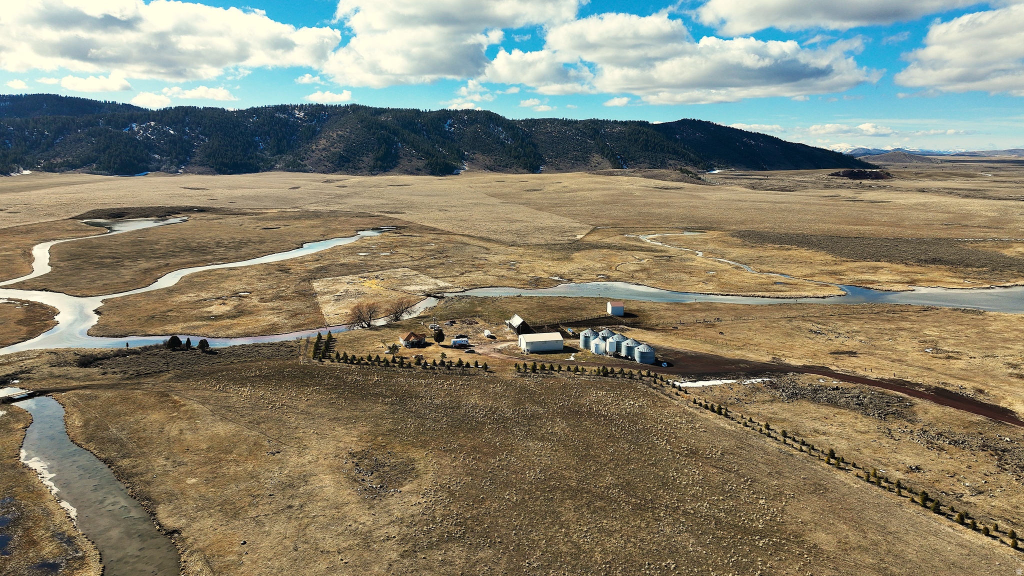 TURNKEY RANCH WITH MEADOW, SODA CREEK, CROPLAND & CRP REVENUE  - Set against the wide-open landscapes of southeastern Idaho, the Hilda Thompson Ranch is an expansive, agricultural holding with recreational value and long-term investment potential. Located approximately four and a half miles northwest of Soda Springs, this historic ranch was first established in the early 1900s as a dry farm and has recently evolved into a productive agricultural and cattle grazing operation with established income streams, water resources and functional infrastructure.  Today, the ranch operates under an efficient rotational grazing system capable of supporting approximately 200 pair of cattle on ground not in CRP. The perimeter is mostly fenced with extensive cross-fencing dividing productive pastures and allowing for sustainable grazing management.  The fencing infrastructure has been upgraded and maintained in very good to excellent condition.  Comprising five contiguous parcels with year-round access and frontage on both sides of Government Dam Road, the property spans a diverse landscape of cropland, open meadow with meandering creek and wildlife habitat.  According to the USDA, 975.36 acres are designated cropland, with approximately 857 acres currently enrolled in the CRP program generating about $50,000 annually, with roughly seven years remaining on the contract. The CRP agreement allows grazing twice during the ten-year term providing additional flexibility for livestock operations.  Water resources are a defining feature of the ranch. Year-round Soda Creek meanders through the property, supporting thriving populations of waterfowl and enhancing both agricultural use and recreational appeal and ultimately feeding into the canal company system for distribution.  The ranch has submitted water rights claims of 3+ CFS on approximately 900 acres which are currently awaiting adjudication within the Bear River Drainage, which presents a potentially meaningful long-term water value.  Infrastructure is comprised of a 2,400 square foot shop, 2,340 square foot original barn, large cattle corral with chute, a three-sided implement and tractor shed, and five aerated grain bins with a combined capacity of 75,000 bushels.  A modest farmhouse originally built around 1945 and remodeled in 1990 offers approximately 842 square feet on the main level plus crawl space for storage.    Additional value includes a cinder mine resource and two short-term leases ending December 31, 2026 involving buildings, infrastructure, and select grazing. For sportsmen and outdoor enthusiasts, the ranch borders expansive public ground managed by the Bureau of Land Management, including the renowned 90 Percent Range, an area carefully managed for healthy mule deer populations. The ranch also hosts a 110-acre wetland habitat project developed through a conservation easement with the Idaho Department of Fish and Game through 2030. Sponsored in part by Ducks Unlimited, the project created an 1,100-foot dike and protected habitat for ducks and swans, complete with a viewing station and parking area.  - 5 Contiguous parcels  - Year-round access & frontage  - Year-round Soda Creek  - USDA designates 975.36 acres cropland - 857+- Acres in CRP  - 3+ CFS Water rights claim submitted for adjudication - Mostly fenced with cross-fencing  - Cinder mine  - Borders BLM  - Farmhouse built around 1945 and remodeled in 1990 with 842 SF on main level plus crawl space - 2,400 SF Shop - 2,340 SF Old Barn - 5 Aerated grain bins with combined capacity of 75,000 bushels  - 3-Sided implement / tractor shed - Large cattle coral and chute - 2 Short term leases ending December 31, 2026 with buildings, infrastructure and some grazing