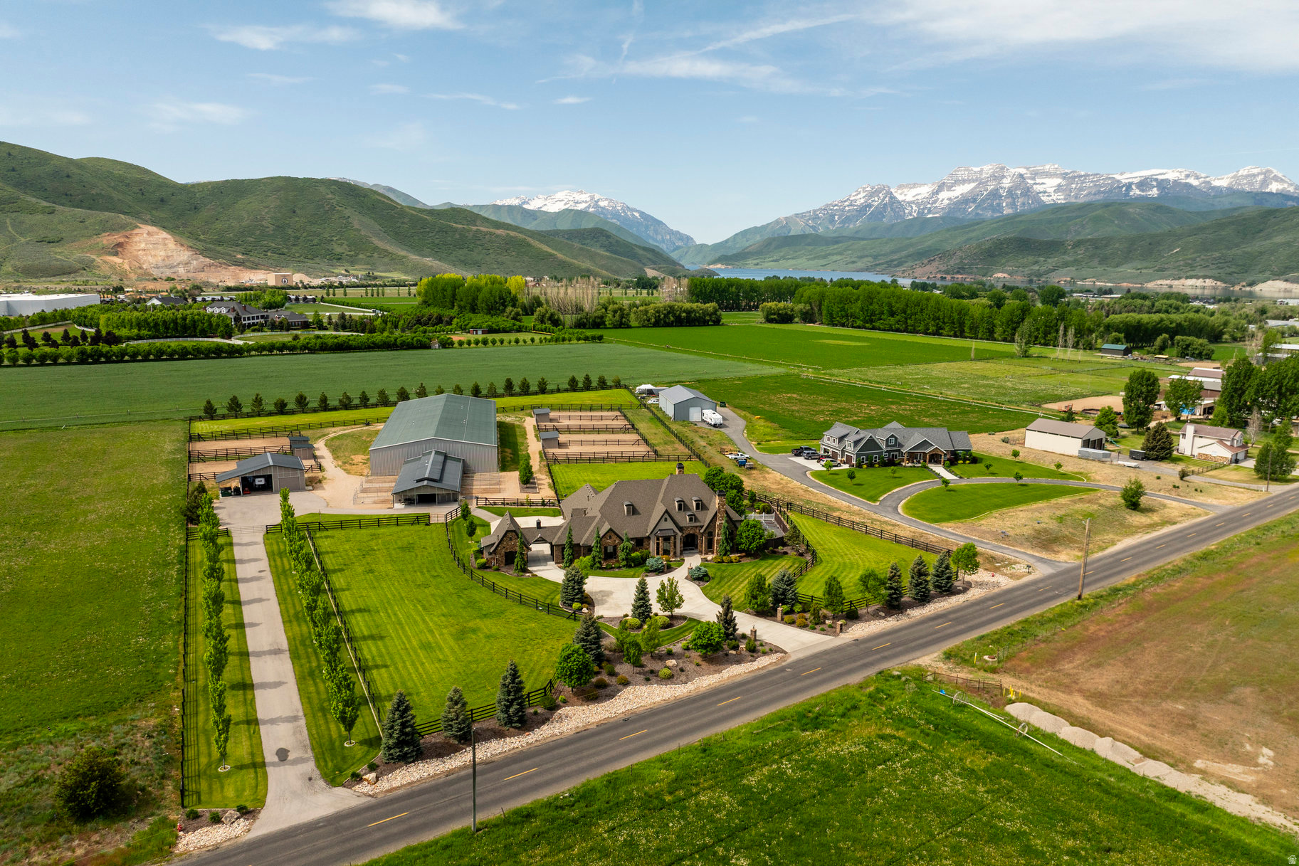 Set on 5.5 impeccably curated acres in the heart of Heber Valley, this extraordinary private equestrian estate captures sweeping, unobstructed views of Mount Timpanogos while delivering a rare combination of refined luxury, elite horse facilities, and year-round recreation. Ideally located just 15 minutes from Park City's world-class ski resorts and minutes from blue-ribbon fly fishing on the Provo River, championship golf, boating, and the Heber Valley Airport. Designed in a timeless French Country style rarely found in Utah, the residence blends elegant craftsmanship with modern convenience. Soaring 10- and 12-foot ceilings, custom millwork, dual laundry rooms, whole-home water filtration and softening systems, and steam humidifiers create an exceptional standard of comfort throughout. The gourmet kitchen is appointed with premium appliances including double ovens, an induction cooktop with gas option, wine refrigeration, and generous gathering spaces designed for entertaining. The main-level primary suite is a true retreat, featuring a private sitting area with panoramic mountain views, a gas fireplace, expansive dual walk-in closets, and a spa-inspired bath with a dedicated laundry area. Outdoor living is equally impressive with a covered patio complete with a built-in Wolf BBQ and fireplace overlooking the surrounding valley and equestrian grounds. Purpose-built for the serious horseman, the estate's fully insulated 36' x 64' MD Barnmaster Elite barn reflects uncompromising attention to detail. Features include radiant gas heat, a 12-foot center aisle with hidden drains and rubber pavers, oversized foaling stall, five 12' x 12' stalls with attached 24-foot runs, heated Ritchie waterers, grooming and wash areas with infrared heaters, premium tack and feed rooms, LED lighting, ceiling fans, and dedicated utility spaces. The attached 75' x 198' heated indoor arena rivals premier professional training facilities, offering exceptional year-round riding conditions with premium GGT footing, European shatterproof safety walls, full-width mirrors, MacroAir fans, LED lighting, integrated sound system, automatic roll-up doors, abundant natural light, and a heated elevated viewing lounge with quartz countertops. Beyond the barn, six spacious turnouts with loafing sheds and five irrigated grass pastures create an ideal environment for equine wellness and performance. Offering privacy, functionality, and luxury at every turn, this is a truly rare legacy property designed for the discerning equestrian buyer seeking an uncompromising mountain lifestyle.