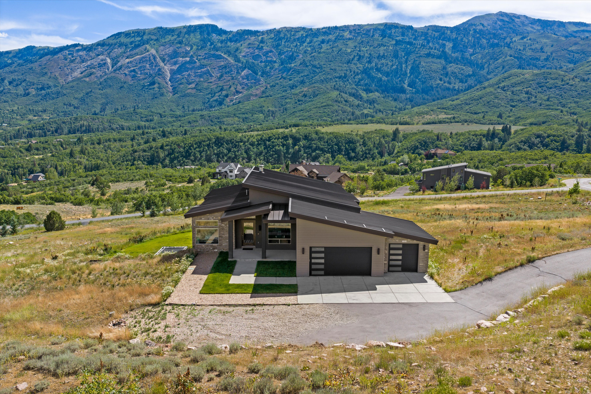 Set on 1.13 acres in Liberty's Durfee Creek Estates, this 2016 contemporary rambler was built around a single idea - the view. Full-wall windows pull Ben Lomond and North Fork Park into the vaulted great room, and the main-level primary suite frames valley and lake views all the way to Pineview. The architecture answers the landscape: clean lines, a standing-seam metal roof, vaulted ceilings, and light from every angle. Main-floor living is effortless - exotic granite countertop waterfalls in the kitchen with gas a range, a primary suite with walk-in closet, separate shower, a freestanding bath tub, a dedicated den/office, central vacuum, and two fireplaces. Downstairs rewrites what a basement can be: a full walkout daylight level that opens straight to the outdoors with the same Ben Lomond and Pineview views as above and none of the below-grade feel. Multiple living and entertaining spaces give the basement room to gather, while three bedrooms - two joined by a Jack-and-Jill bath and a third full en suite - keep family and guests comfortable. Every bedroom has a bathroom. Covered outdoor living, a 3-car garage with RV parking, and 4,954 finished square feet complete it, minutes from Pineview Reservoir, Powder Mountain, Snowbasin, and the trails of North Fork Park. Some homes have a view. This one was designed for it.