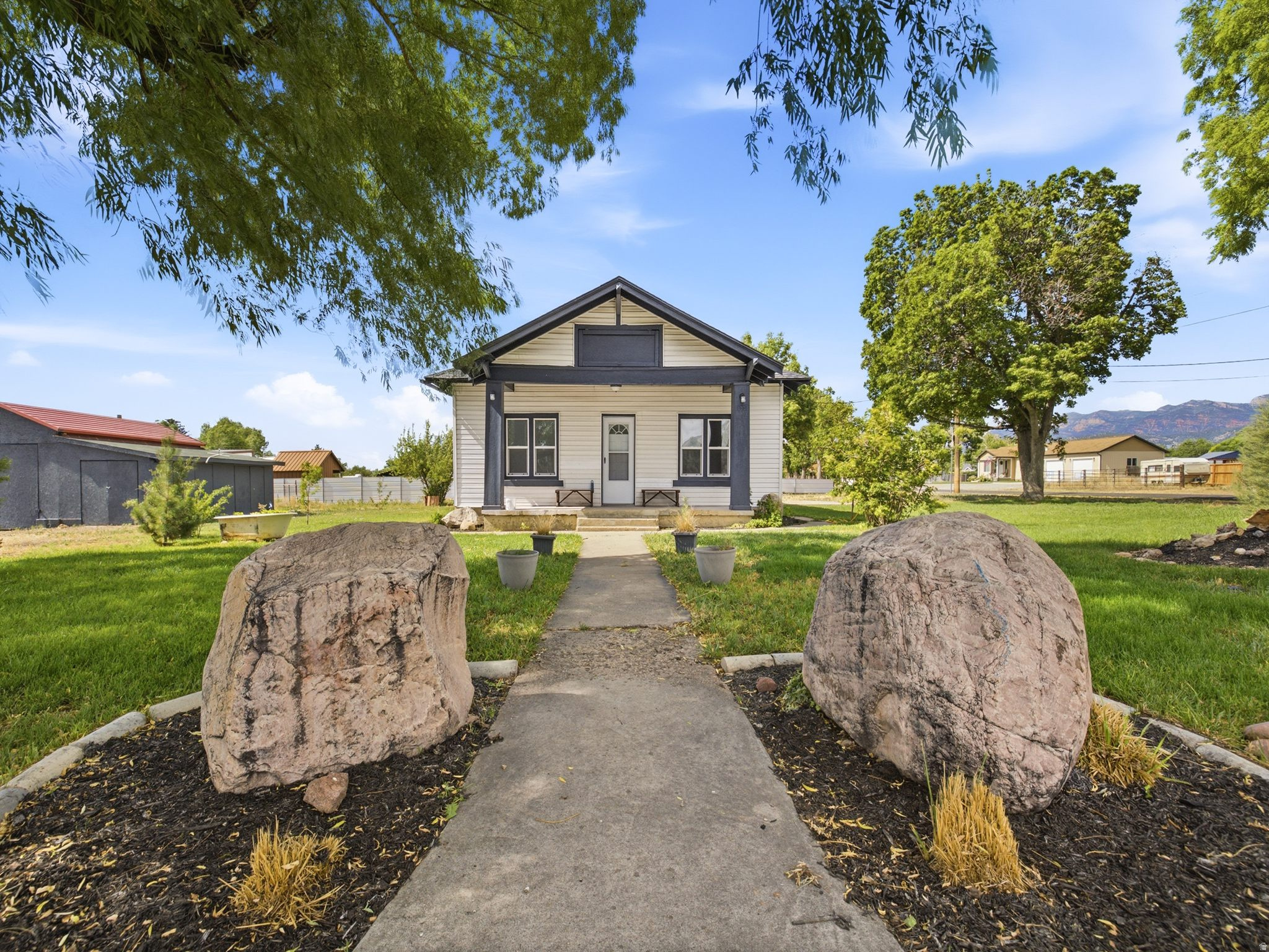 There's a charming craftsman bungalow in the heart of one of central Utah's most quietly coveted small towns. Tucked on a generous lot, this freshly updated home sits beneath a canopy of mature trees with the Nebo Range rising to the east and wide open valley views stretching in every direction. If you have been searching for something that feels like it belongs to a different pace of life, this is it. The curb appeal tells the story before you even step inside. A covered front porch with bold dark trim and twin bench seats invites you to sit and stay. Large boulder accents frame the concrete walk, and mature trees shade the front lawn, giving the property a settled, established feel that new construction simply cannot replicate. Inside, new luxury vinyl plank flooring flows throughout every room, paired with fresh white walls and matte black ceiling fans that give the home a clean, modern edge while honoring its craftsman bones. The living areas are connected by a graceful arched doorway, a detail that stops people mid-tour every time. The kitchen offers abundant warm wood cabinetry, open corner shelving, updated countertops, a black dishwasher, and a window above the sink that frames a mountain view. The dedicated laundry room with its rich wood paneling and full size Samsung washer and dryer is a practical bonus that buyers rarely overlook. Bedrooms are bright and generously sized, each with dual windows that pull in natural light from multiple directions. The bathroom is clean and updated with a solid surface vanity and tub and shower combo. A full unfinished basement with a built in workbench provides serious storage or future finishing potential. The backyard lot extends well beyond the home and includes an outbuilding, giving you the kind of space for projects, animals, or expansion that is nearly impossible to find at this price point. Levan sits at the base of the mountains south of Mt. Nebo, with Chicken Creek and Pigeon Creek canyons flanking the east side of town, offering fishing, four wheeling, hiking, and camping just minutes away. The town park features a full playground, pavilions, a baseball diamond, and a splash pad. Yuba State Park and Lake Yuba are a short drive south. Nephi is just up the road for shopping, dining, and freeway access.  Come walk through it and see how much living fits inside this one.